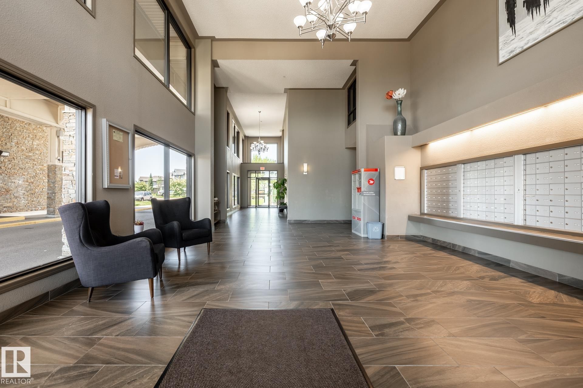 Spacious lobby featuring a chandelier, large format tile flooring, high ceilings, and extensive window-line - 330 1520 Hammond Gate Gate, Edmonton, AB