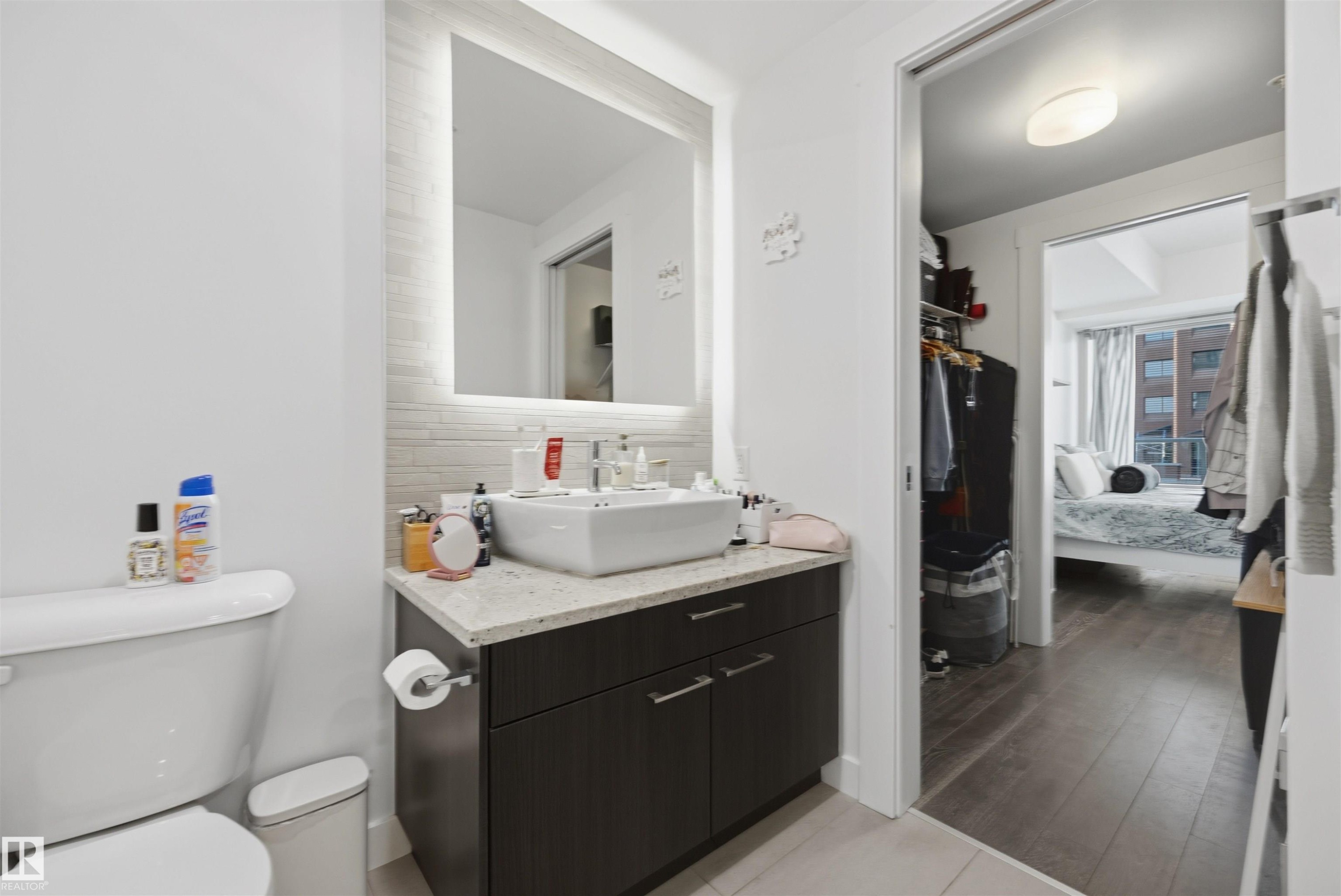 Modern bathroom featuring a rectangular vessel sink, stone-finish countertop, and dark wood-finish vanity - #802 9720 106 St Nw, Edmonton, AB - Indoor Photo Showing Bathroom