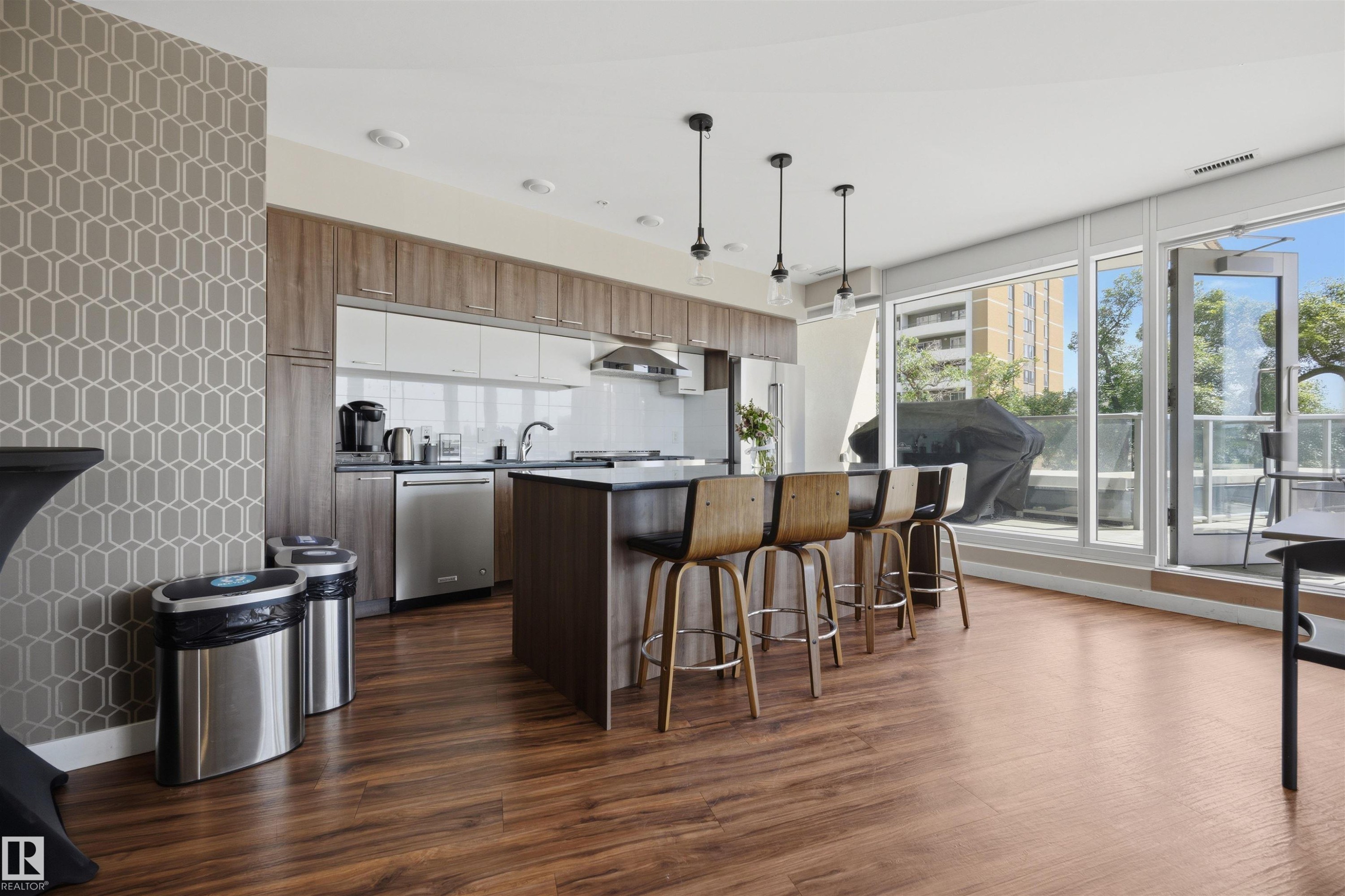 Modern kitchen featuring wood-finish flooring and a large island with seating - #802 9720 106 St Nw, Edmonton, AB - Indoor Photo Showing Other Room