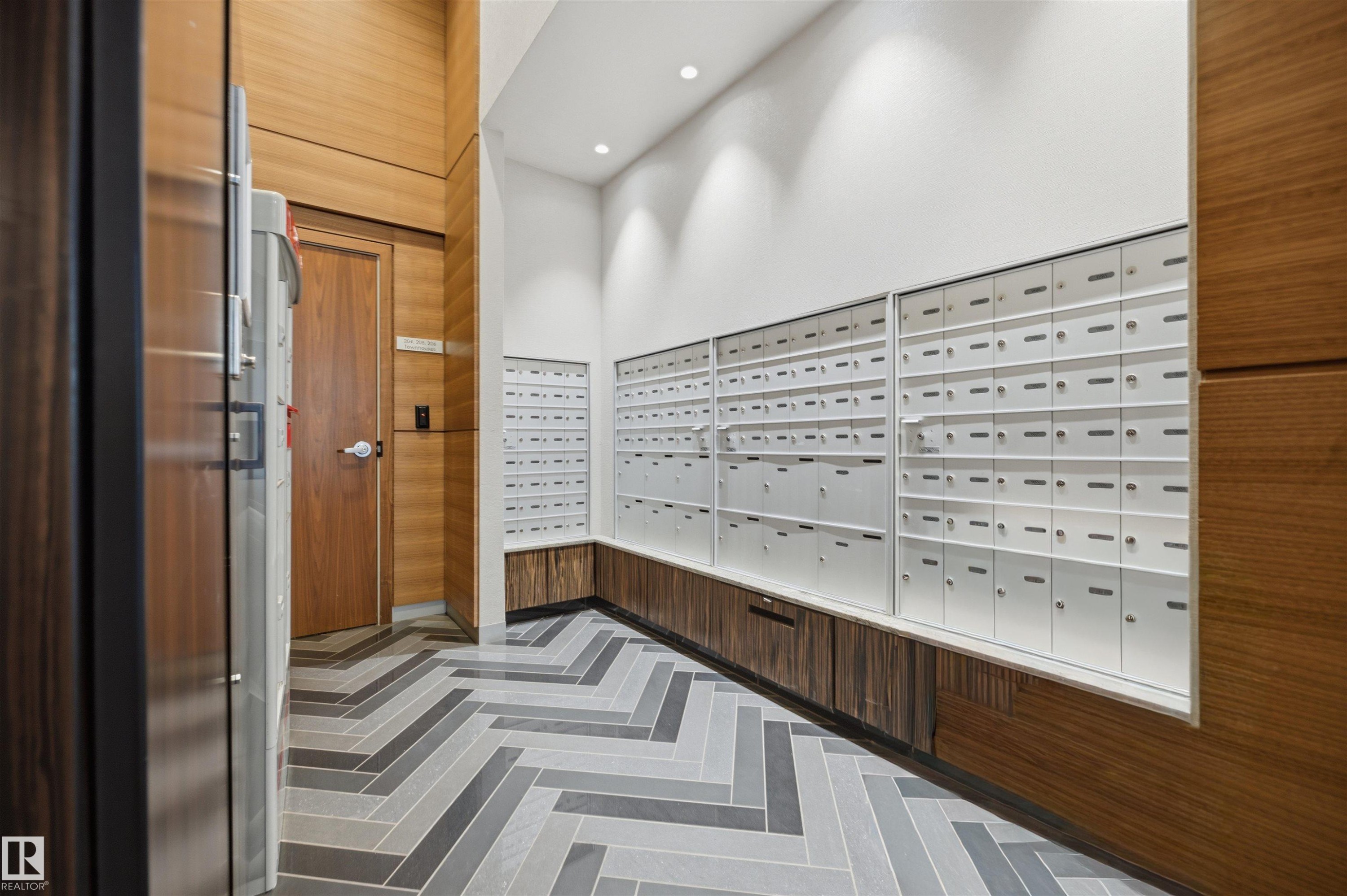 Modern mailroom featuring an extensive bank of individual mailboxes - #802 9720 106 St Nw, Edmonton, AB - Indoor Photo Showing Other Room