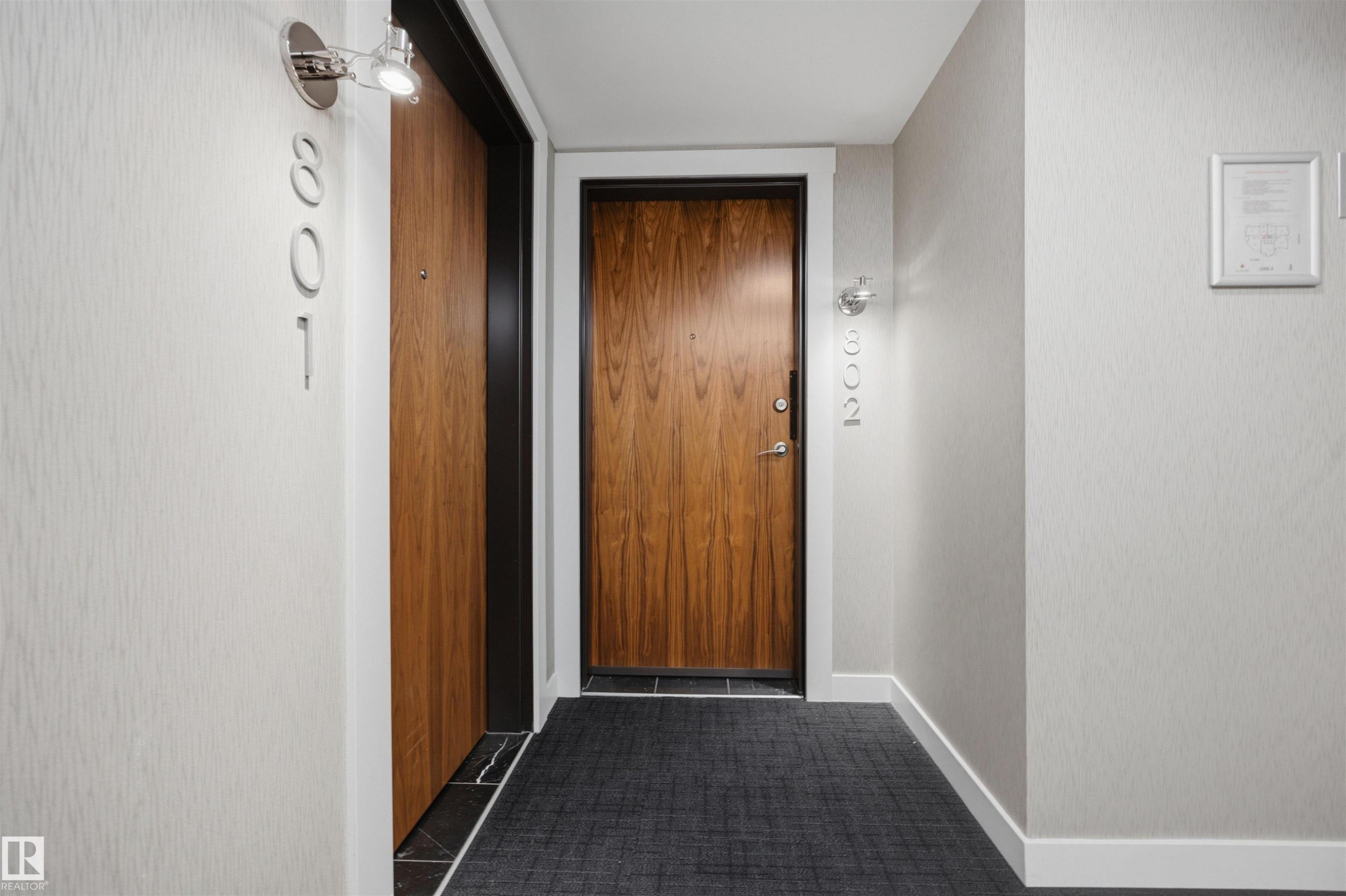 Entryway with a wood-finish door and modern door hardware - #802 9720 106 St Nw, Edmonton, AB - Indoor Photo Showing Other Room