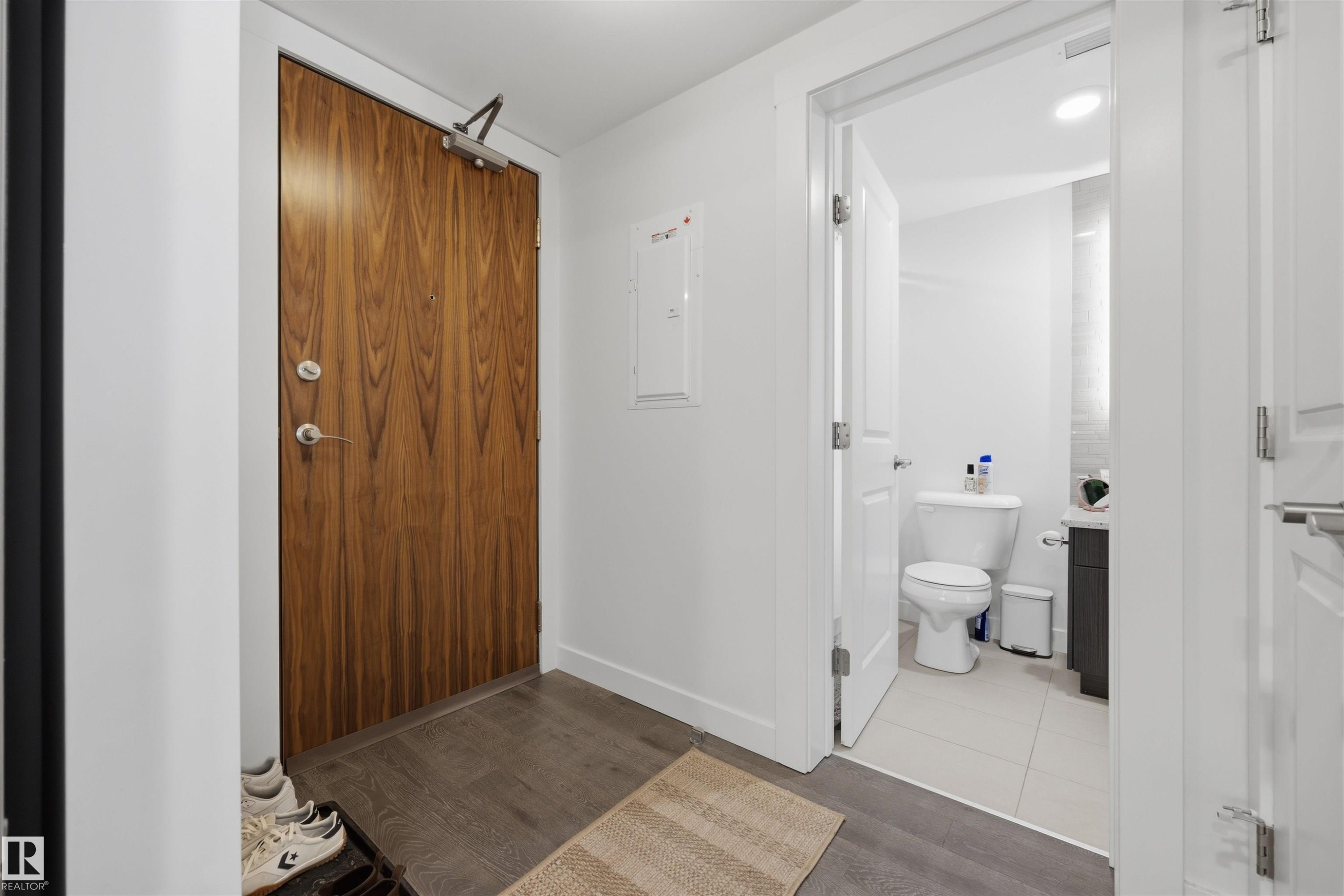 Rich wood-finish entry door with modern hardware - #802 9720 106 St Nw, Edmonton, AB - Indoor Photo Showing Other Room