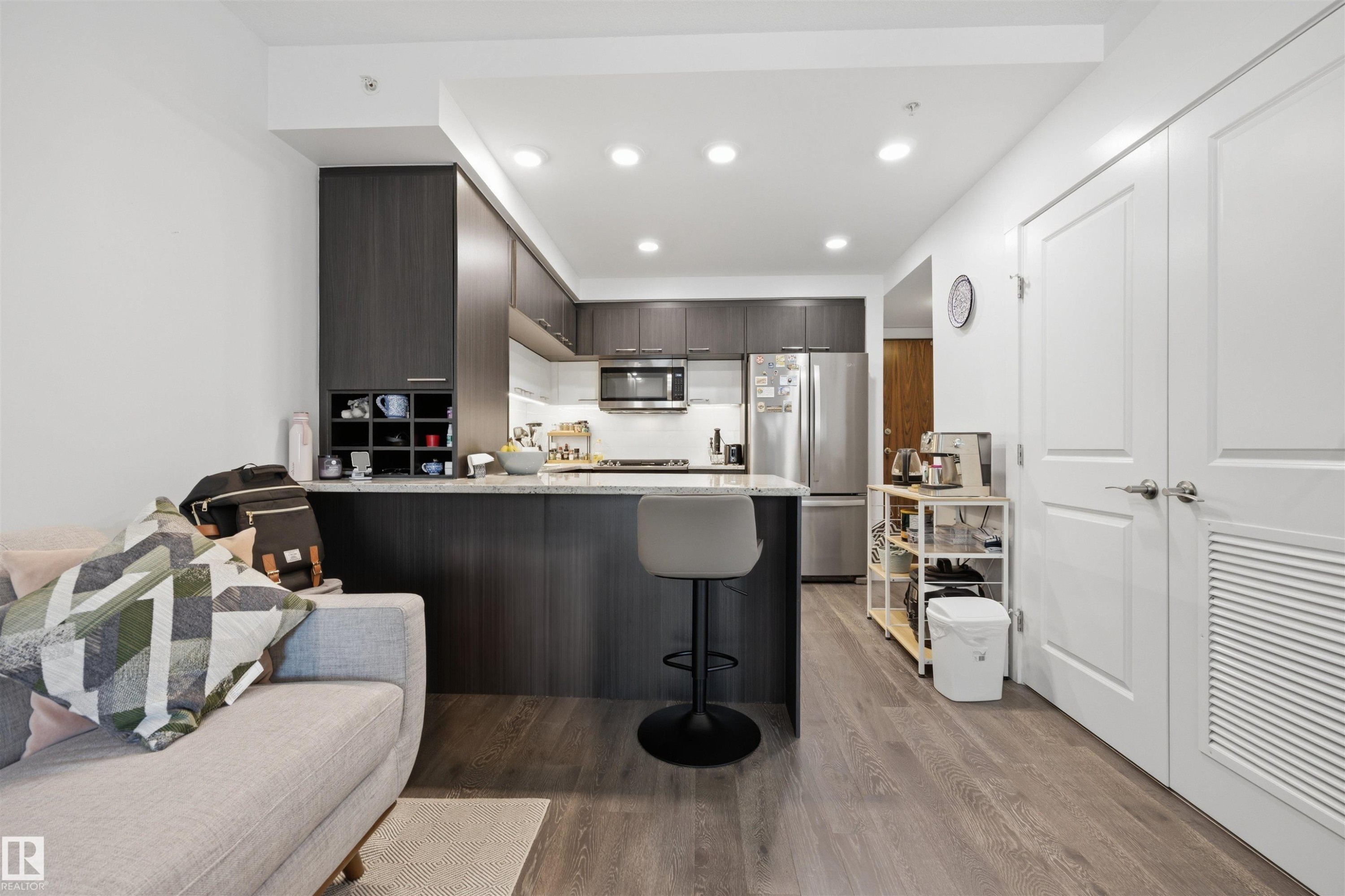 Contemporary kitchen with dark wood-finish cabinetry, stainless steel appliances, and recessed lighting - #802 9720 106 St Nw, Edmonton, AB - Indoor Photo Showing Kitchen With Upgraded Kitchen