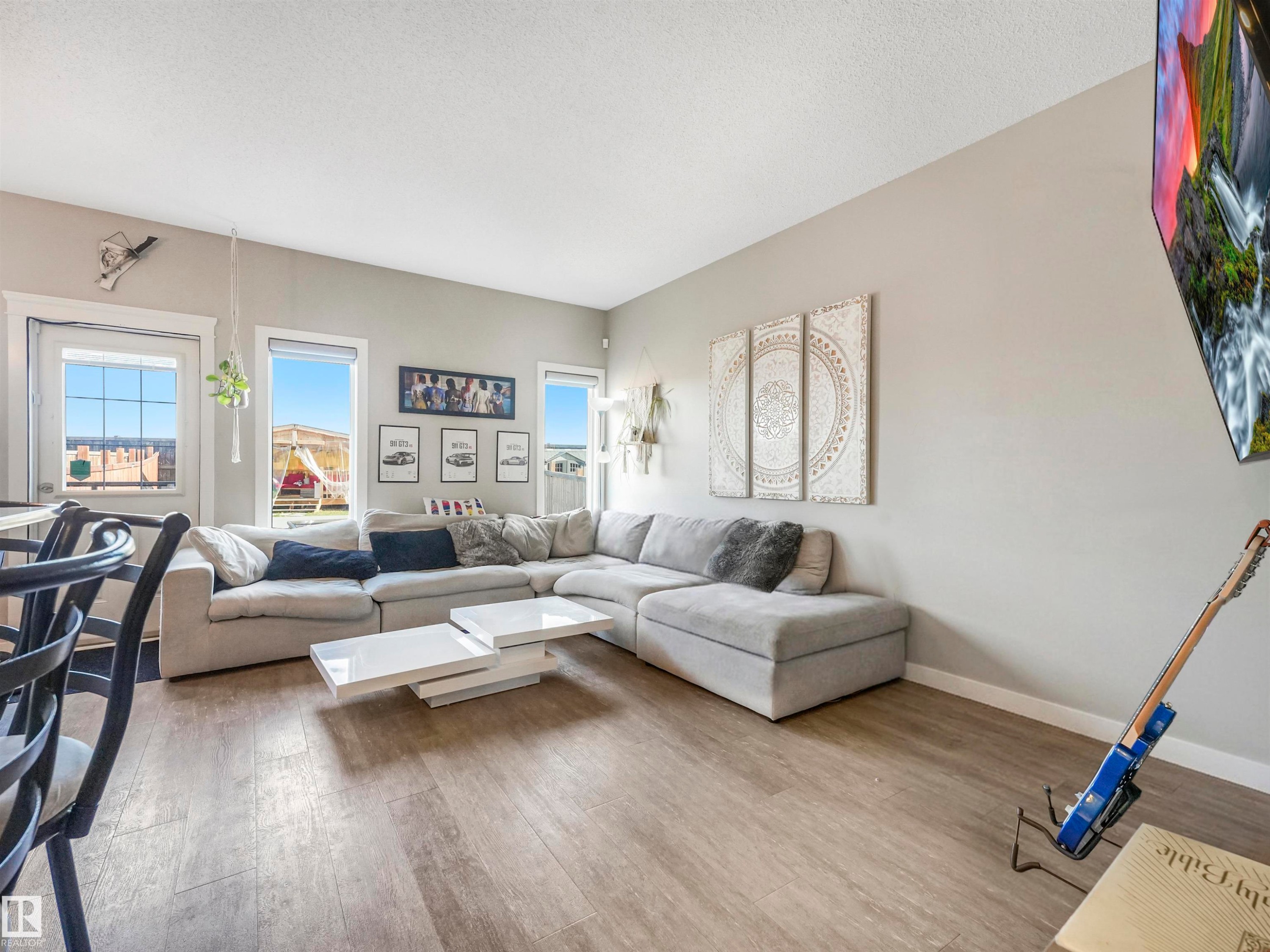 Spacious living area featuring light wood-finish flooring, light gray wall paint, and multiple large windows for abundant natural light - 17171 38 Street, Edmonton, AB