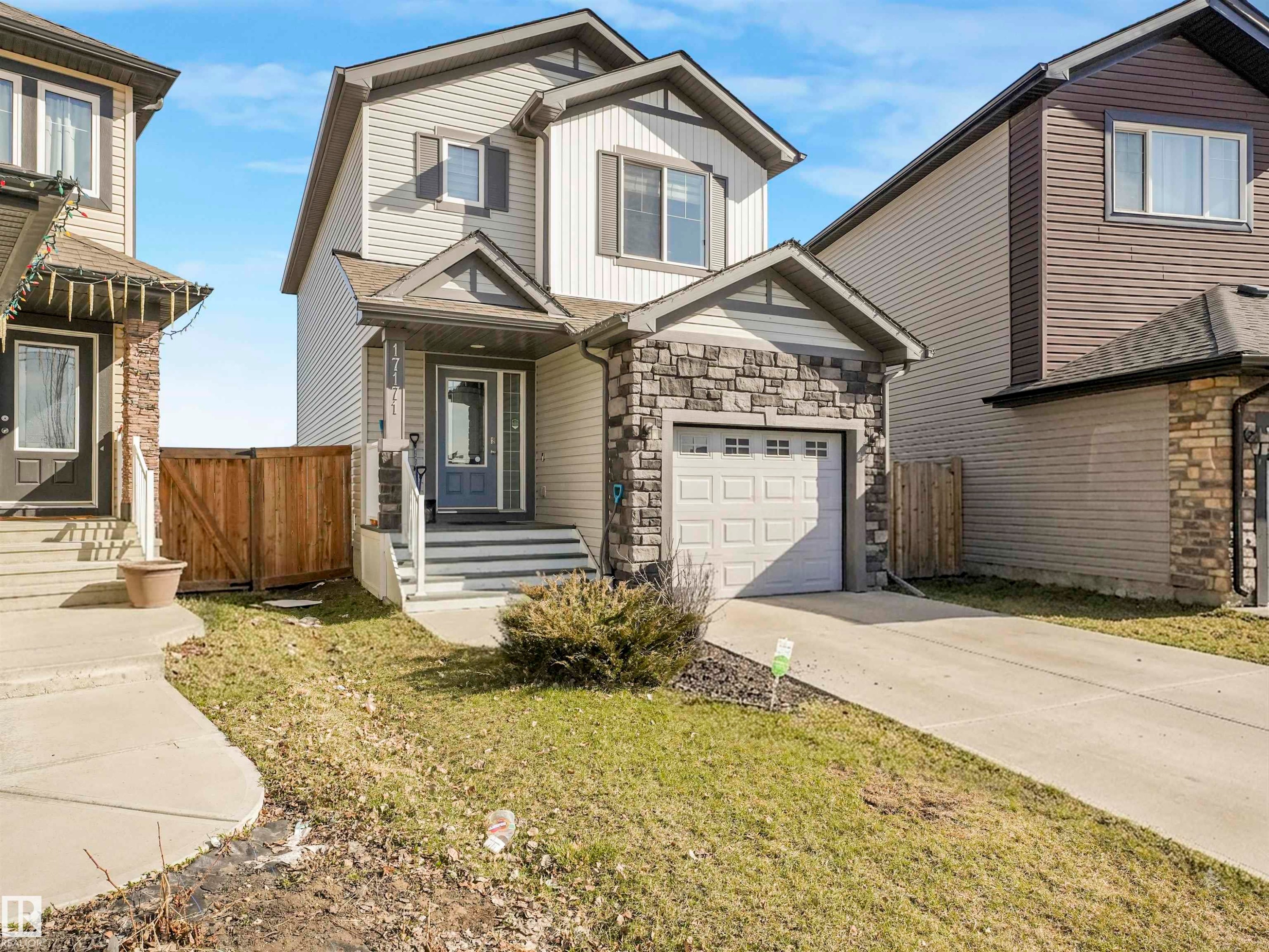 Two-story residence featuring light-colored siding and a stone-clad garage - 17171 38 Street, Edmonton, AB