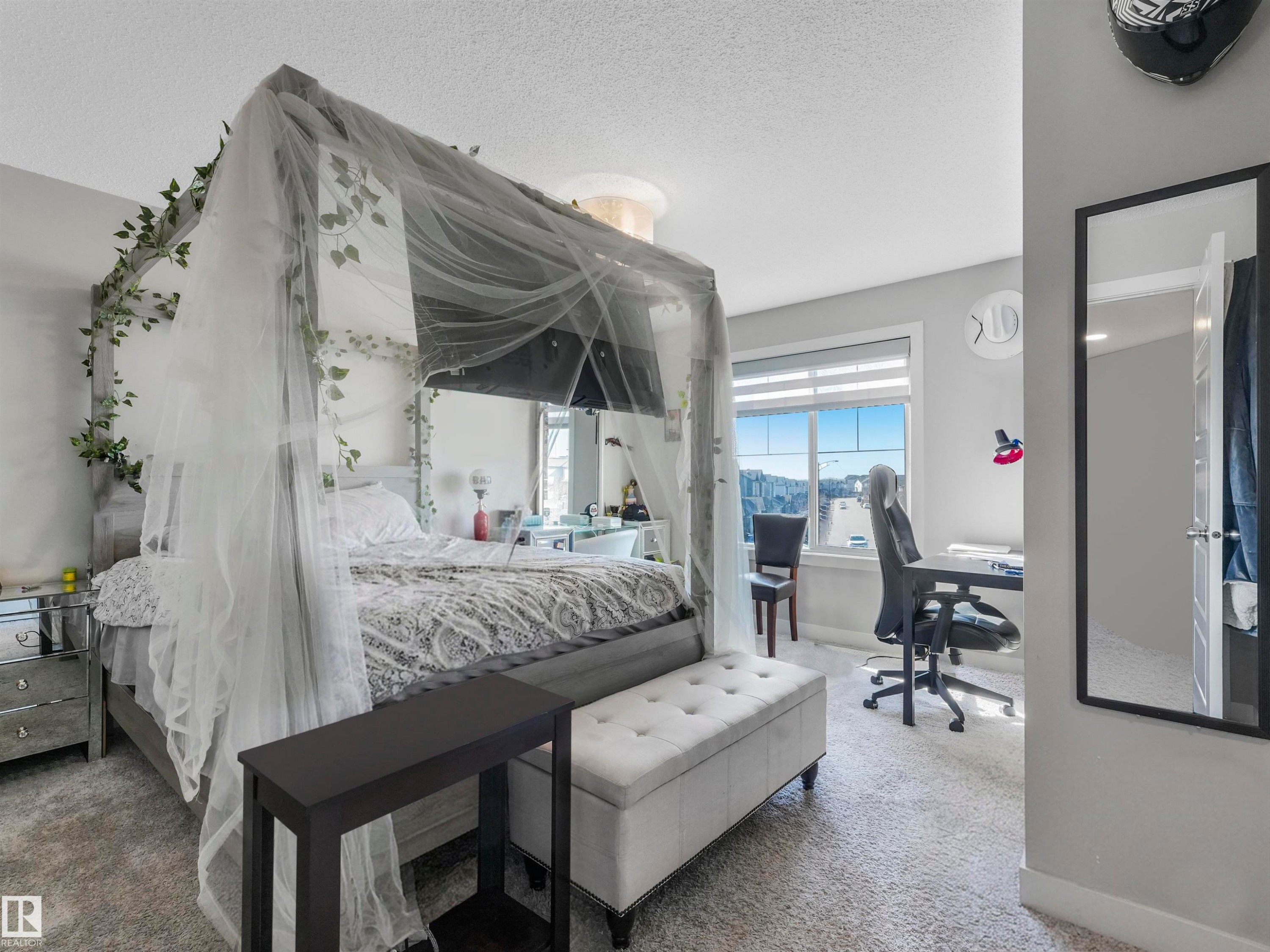 Carpeted bedroom with a large window, light gray wall paint, and a white door with black hardware - 17171 38 Street, Edmonton, AB