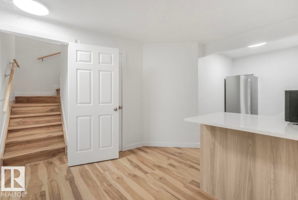 Wood-finish flooring throughout, featuring a staircase with natural wood treads and handrail - 17171 38 Street, Edmonton, AB