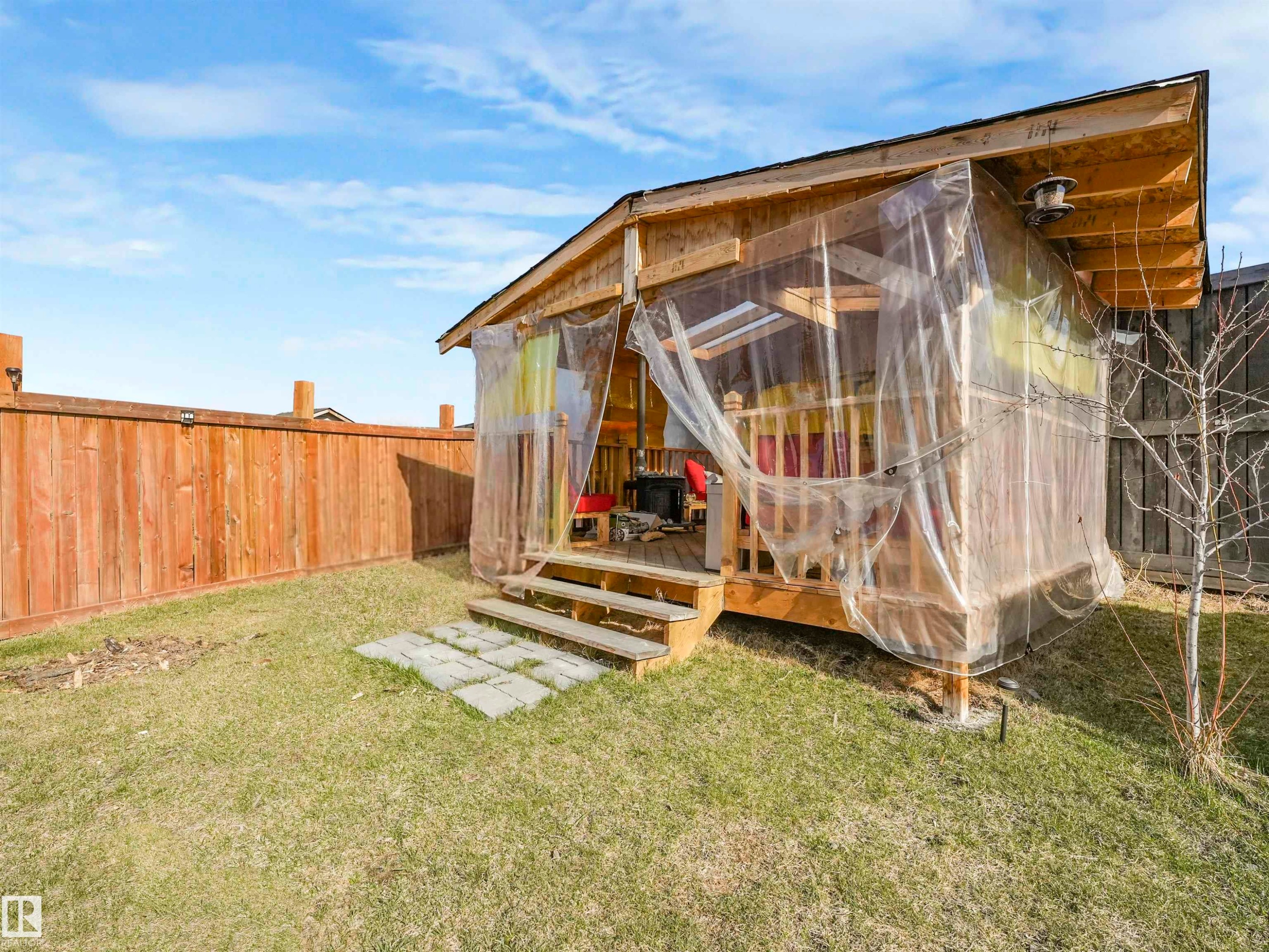 Wooden outdoor structure with a sloped roof and an elevated deck, featuring clear plastic sheeting enclosure - 17171 38 Street, Edmonton, AB