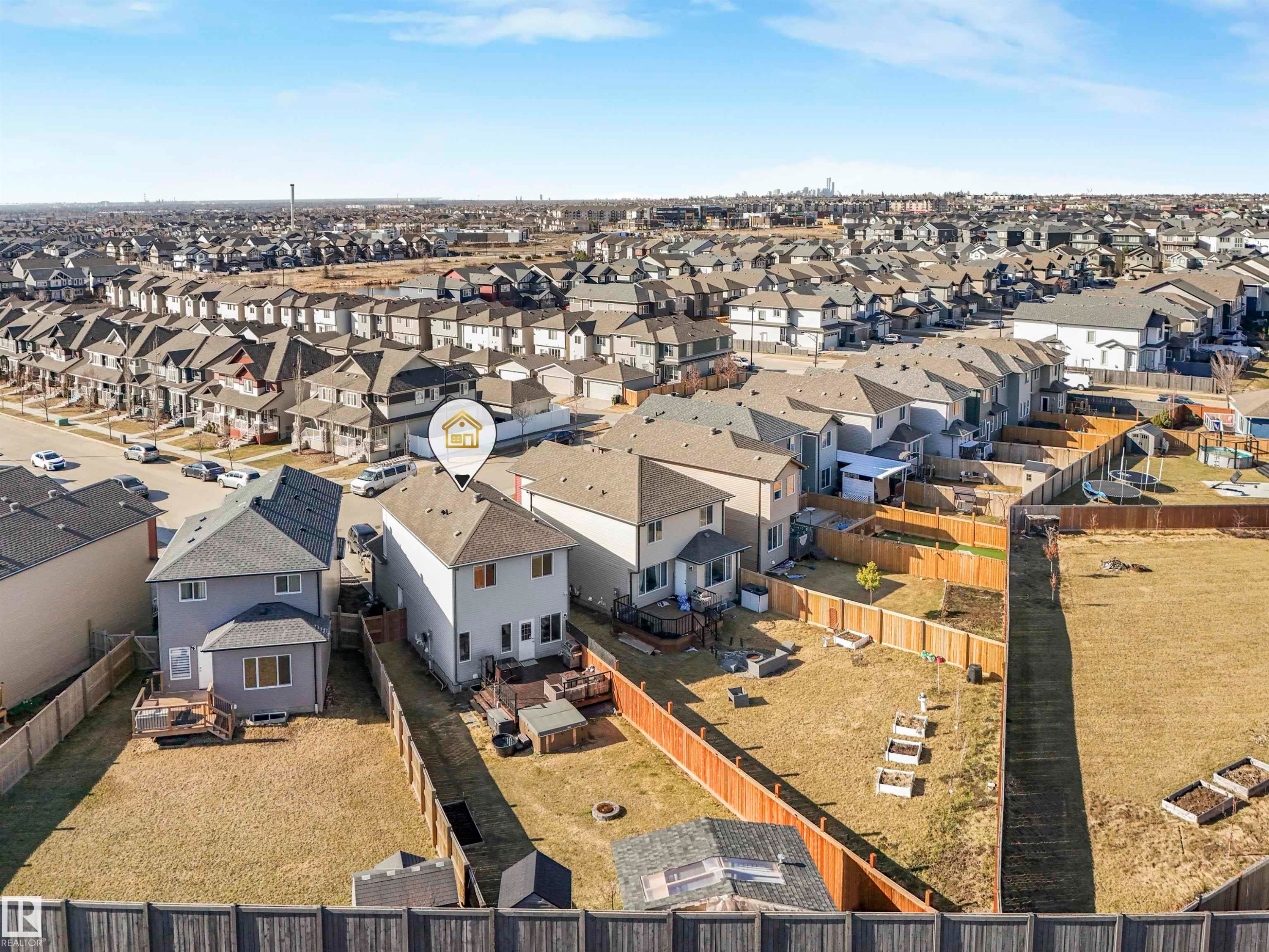 Rear exterior of the property featuring a wooden deck, a fenced yard, and garden beds - 17171 38 Street, Edmonton, AB