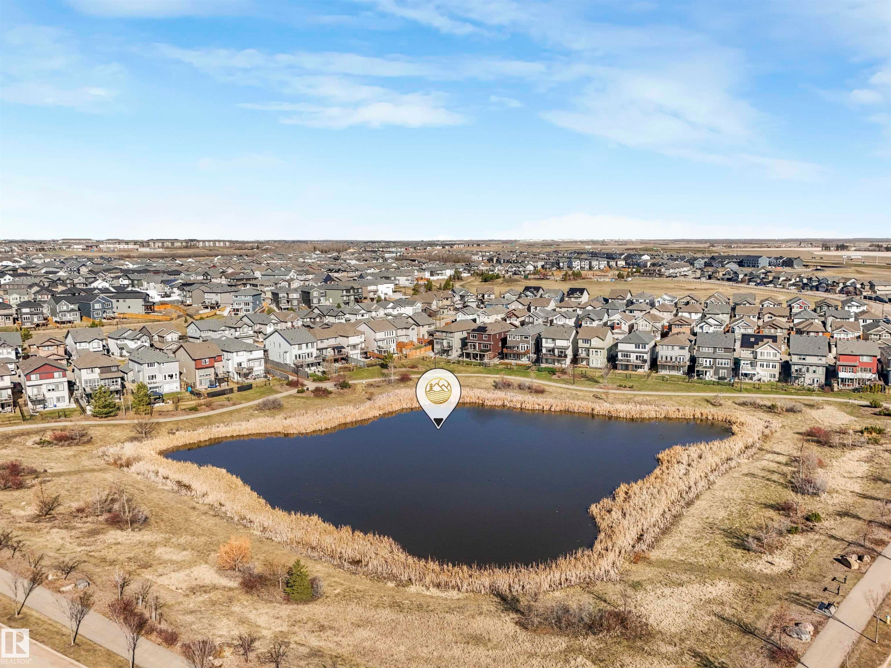 Aerial neighborhood overview showcasing a pond surrounded by natural landscaping and walking paths - 17171 38 Street, Edmonton, AB