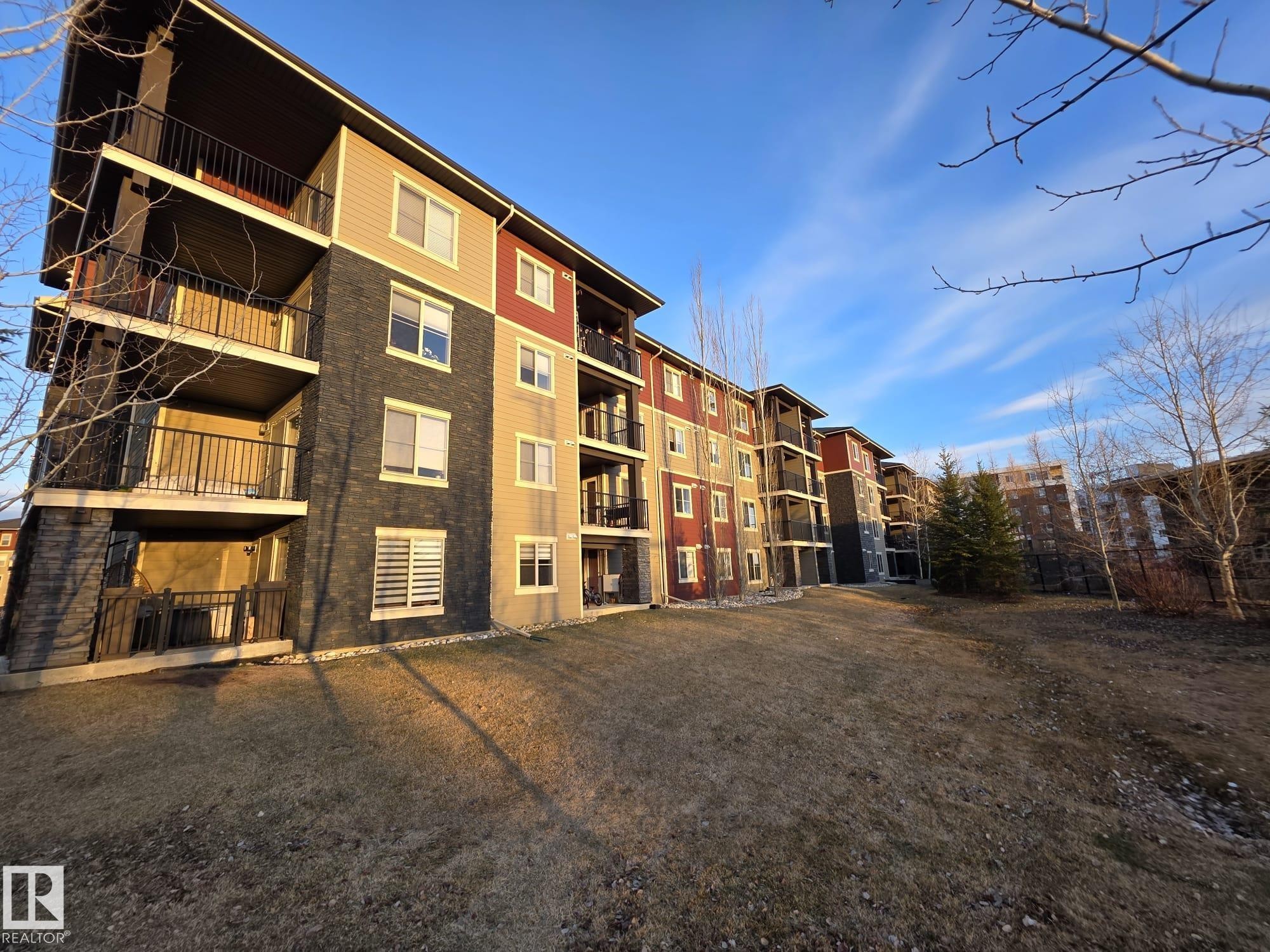 Multi-story residential building featuring diverse exterior finishes including siding and stone-look panels - 206 12045 22 Avenue, Edmonton, AB