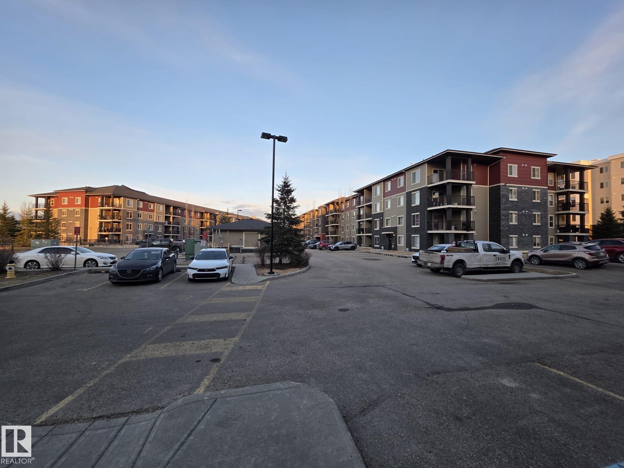 Multi-story apartment building featuring balconies, a mix of panel siding, and stone facade - 206 12045 22 Avenue, Edmonton, AB