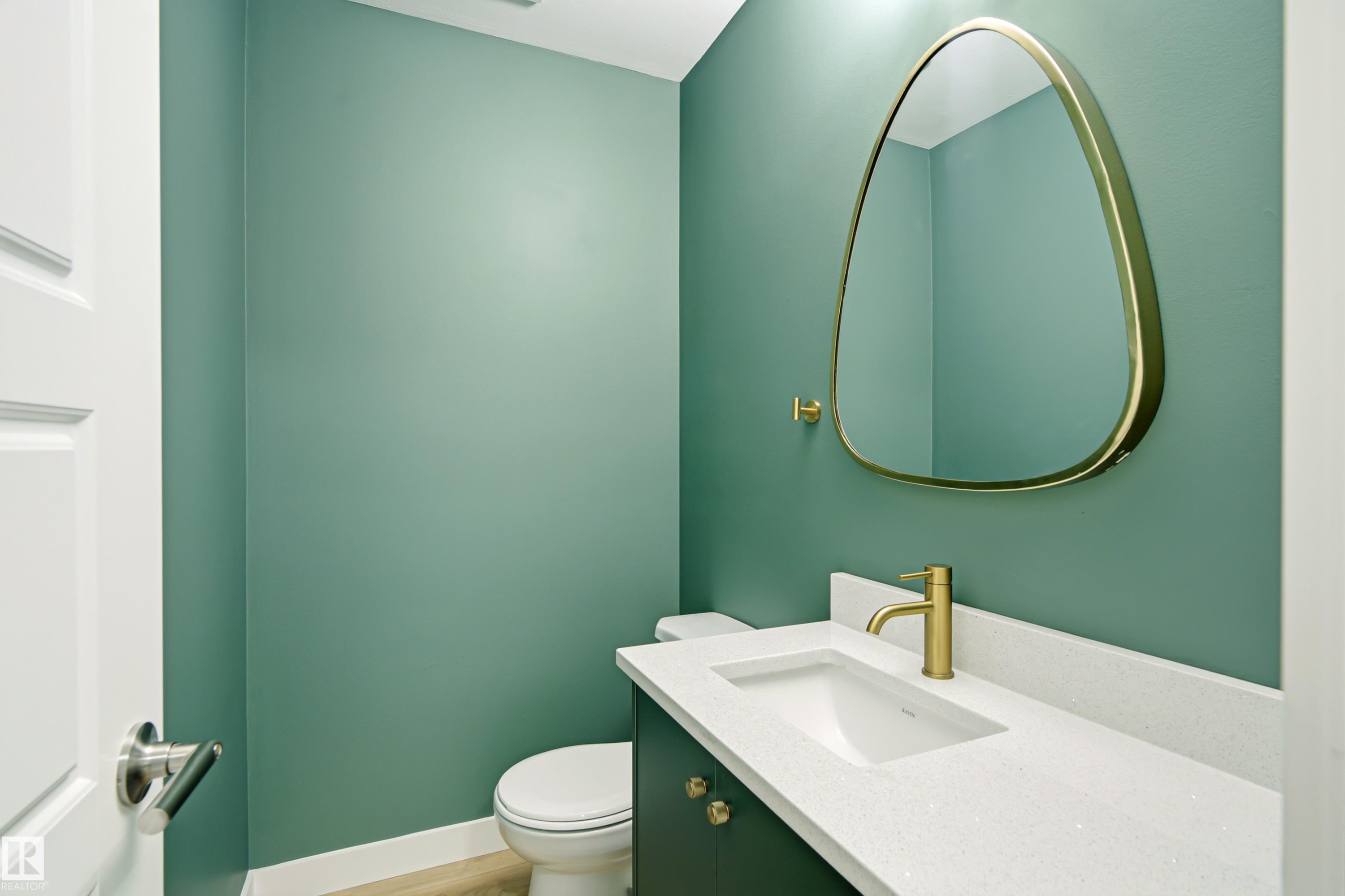 Powder room featuring a sleek vanity with an integrated sink, a white stone-finish countertop, and a modern gold-toned faucet - 18217 84 Avenue Nw, Edmonton, AB