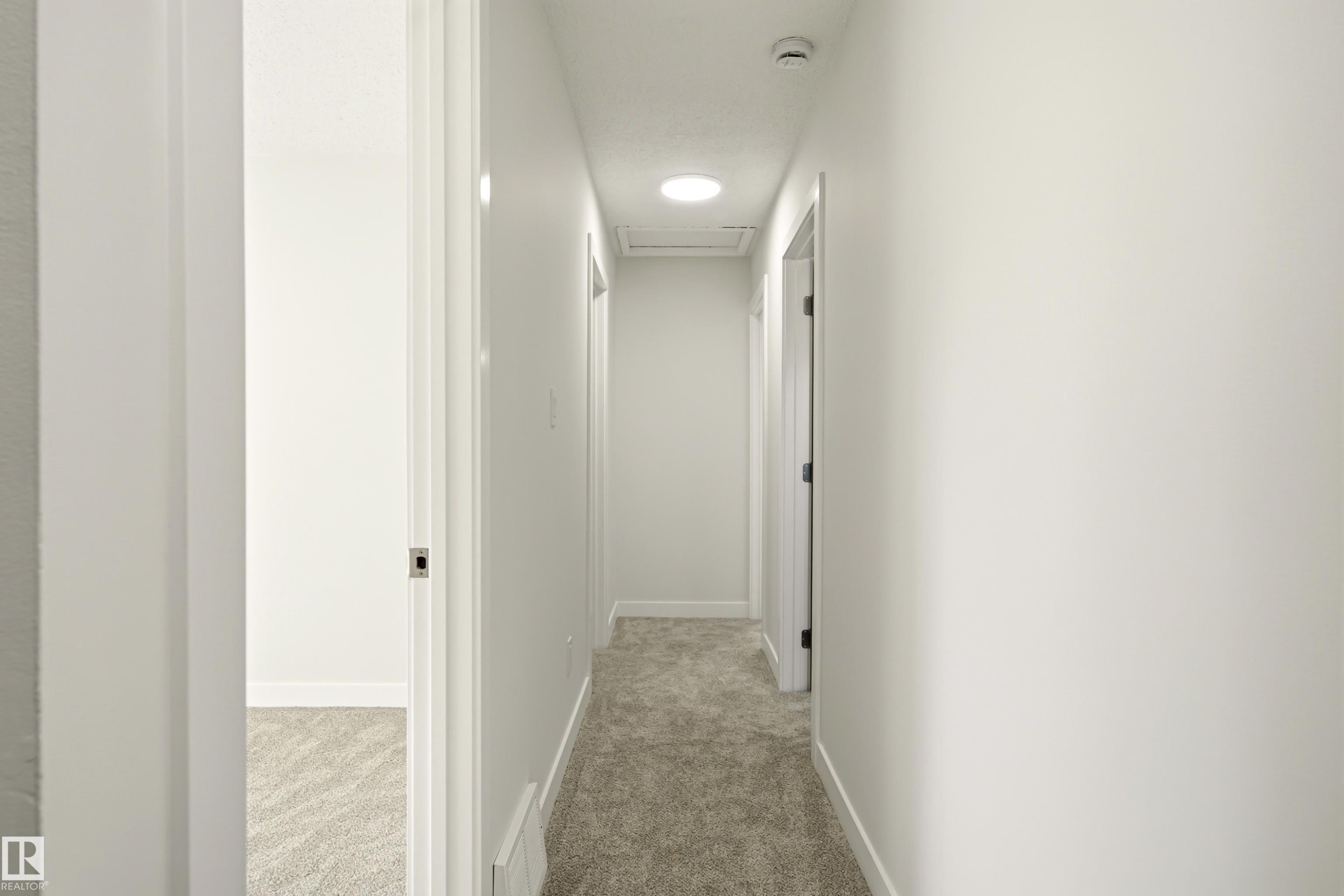 Interior hallway featuring light-toned carpeting, white walls, and recessed lighting - 18217 84 Avenue Nw, Edmonton, AB