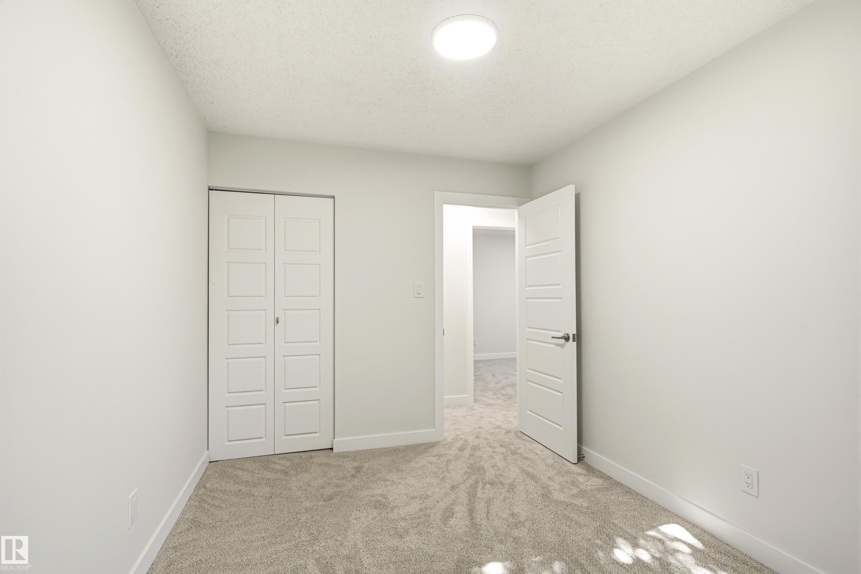 Neutral-toned carpeting paired with white walls, a white ceiling, and a flush-mount overhead light fixture - 18217 84 Avenue Nw, Edmonton, AB