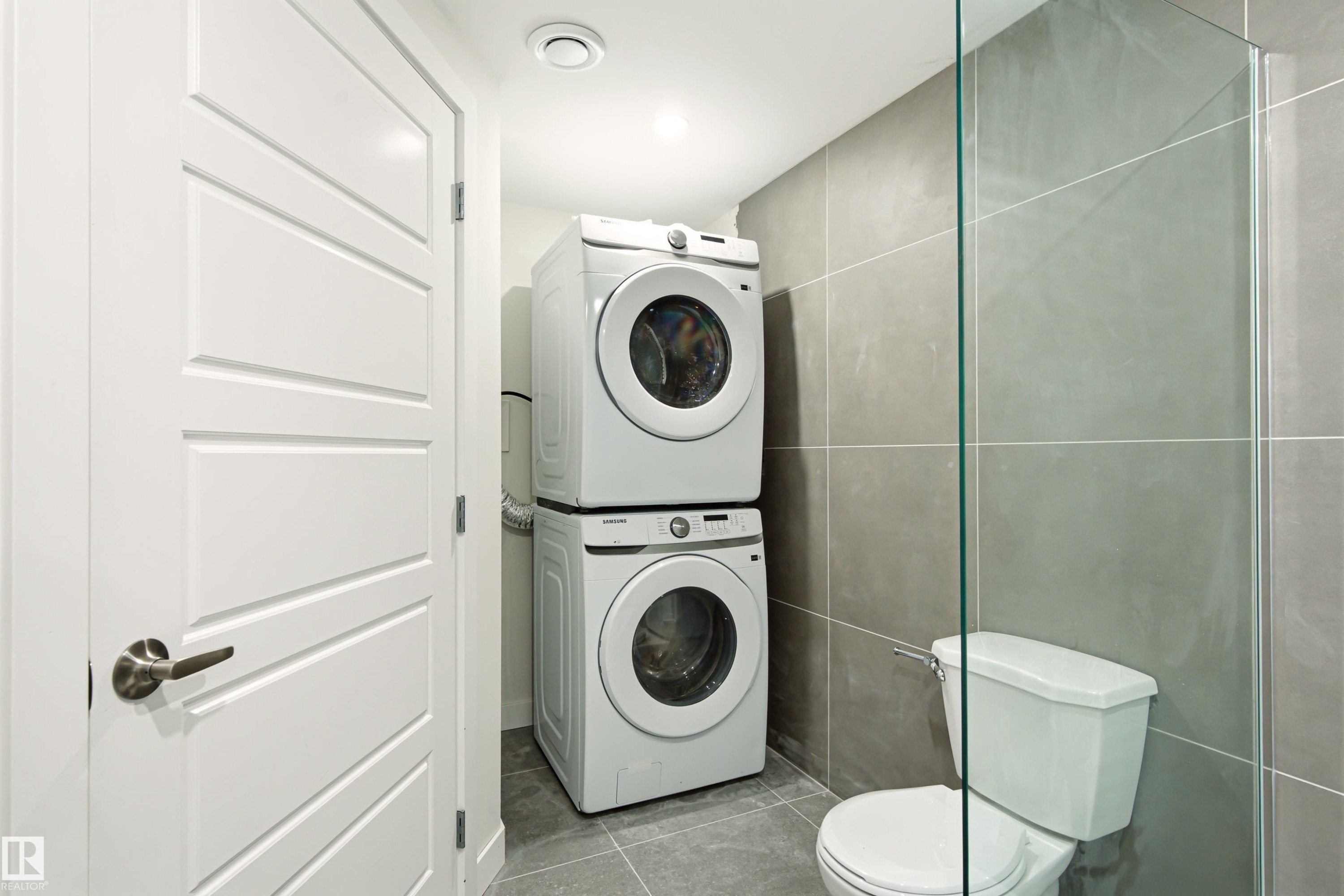 Compact laundry area with stacked washer and dryer units - 18217 84 Avenue Nw, Edmonton, AB