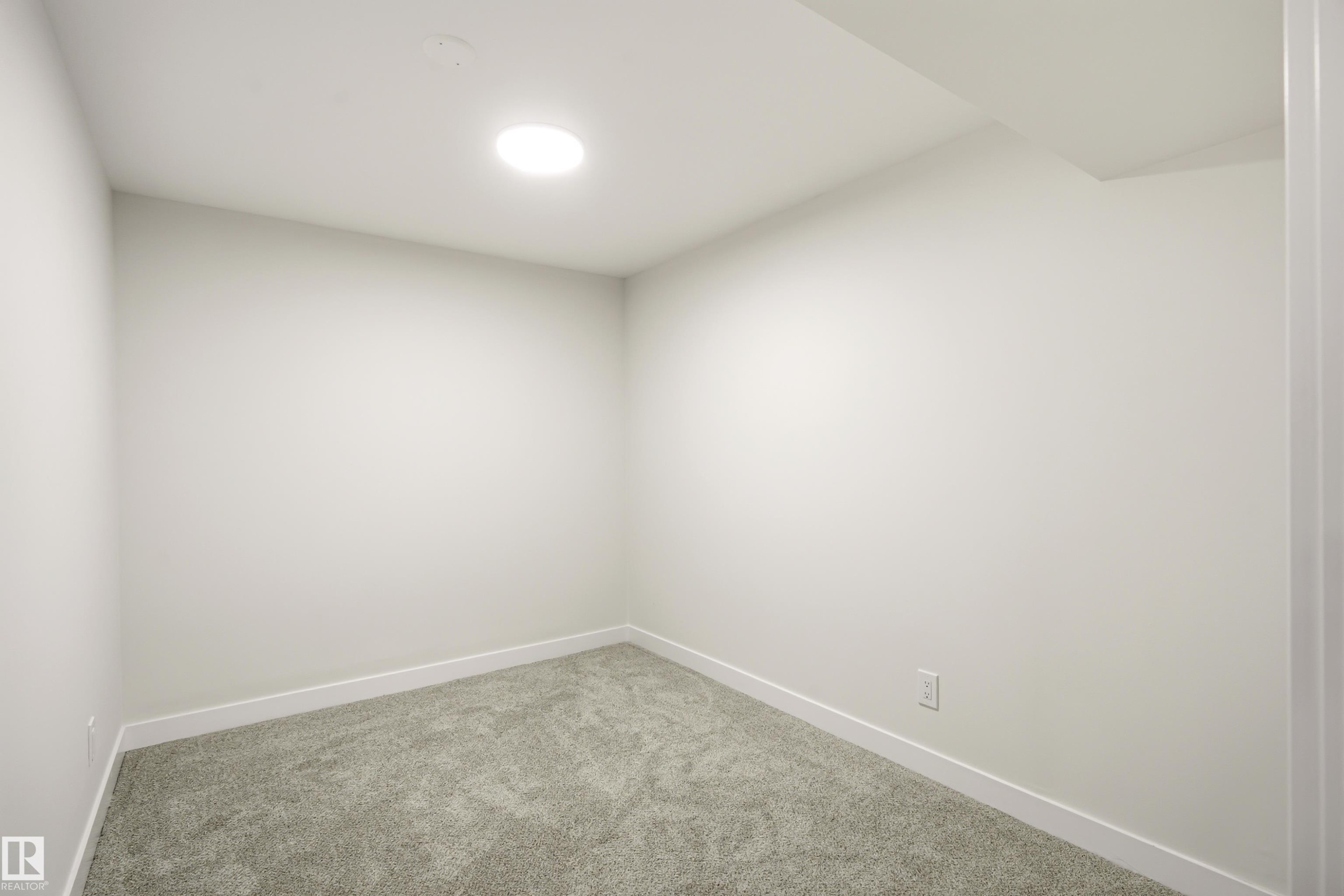 Neutral-toned room featuring a recessed circular light fixture, light gray carpeting, white walls, and clean white baseboards - 18217 84 Avenue Nw, Edmonton, AB