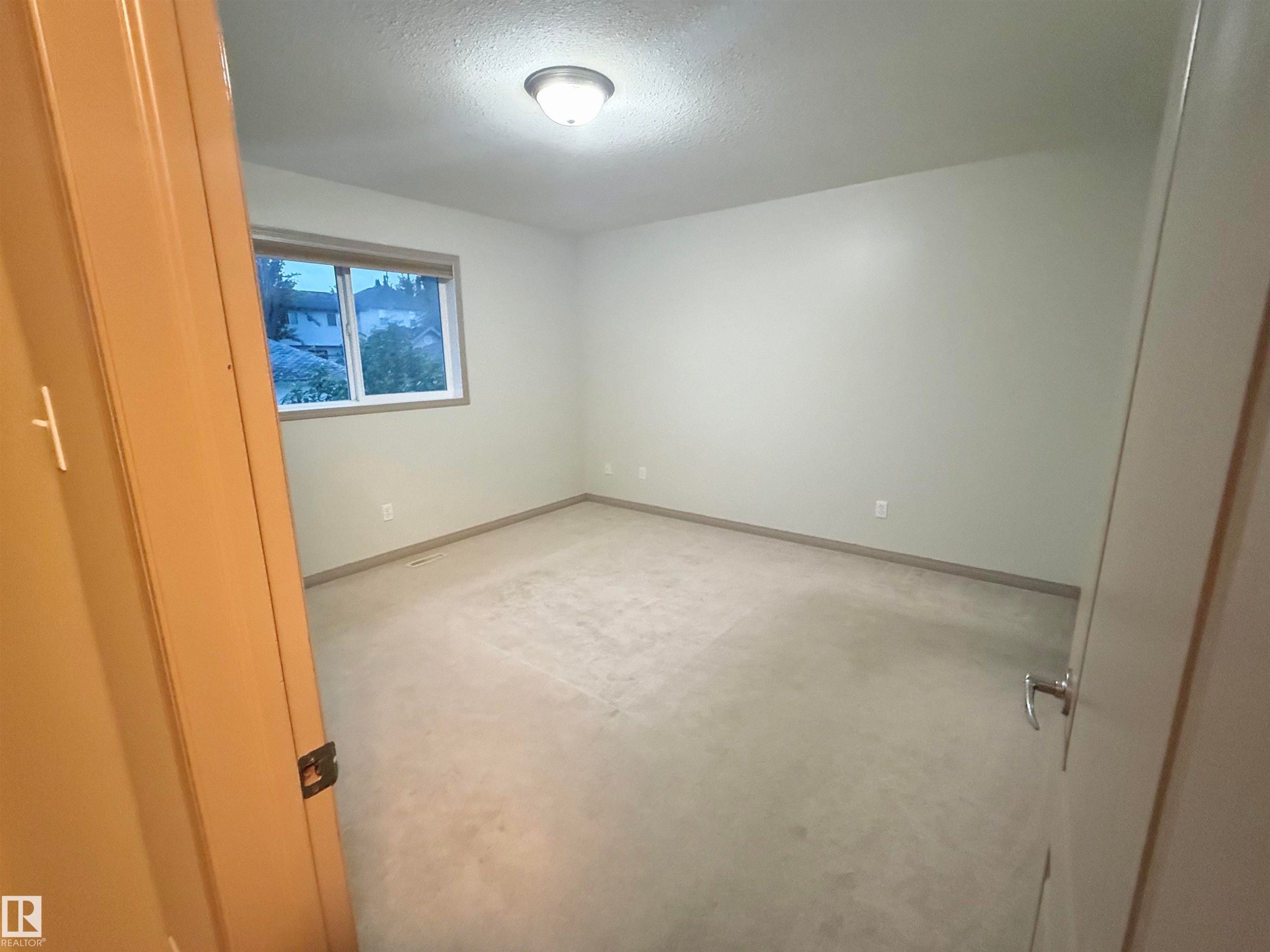Neutral-toned room featuring a single window with blinds, carpet flooring, a flush-mount ceiling light fixture, and light-colored walls with baseboards - 1978 Tomlinson Green Green, Edmonton, AB