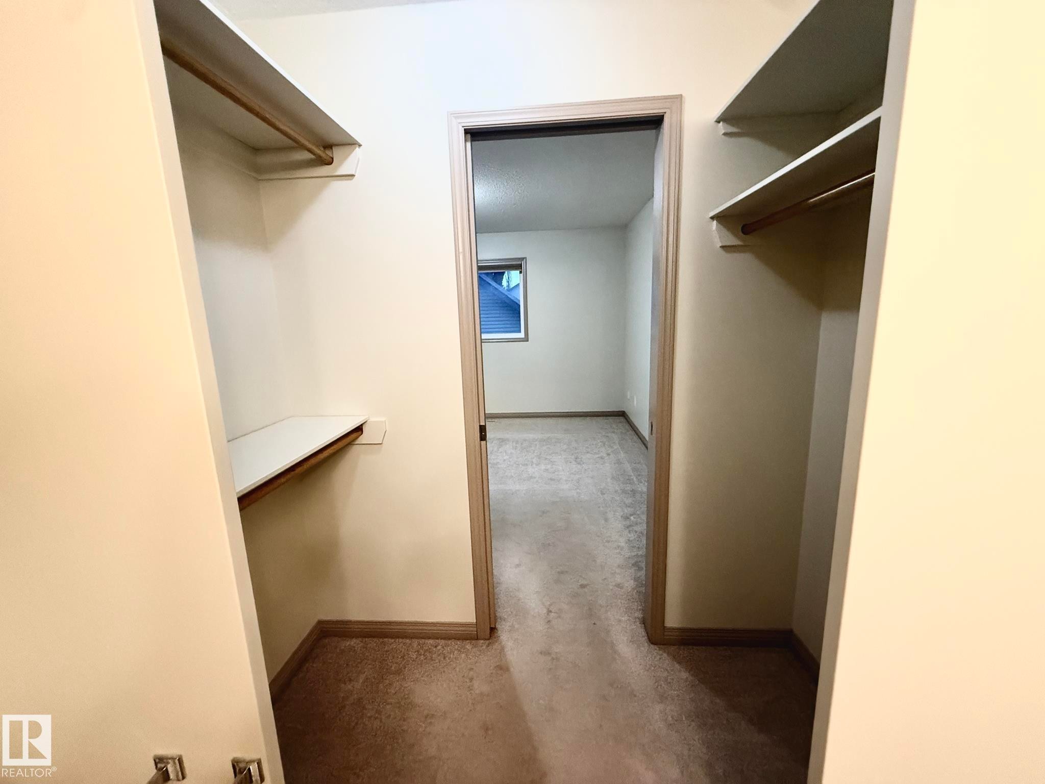 Walk-in closet featuring dual hanging rods, built-in shelving, carpet flooring, and neutral wall paint - 1978 Tomlinson Green Green, Edmonton, AB