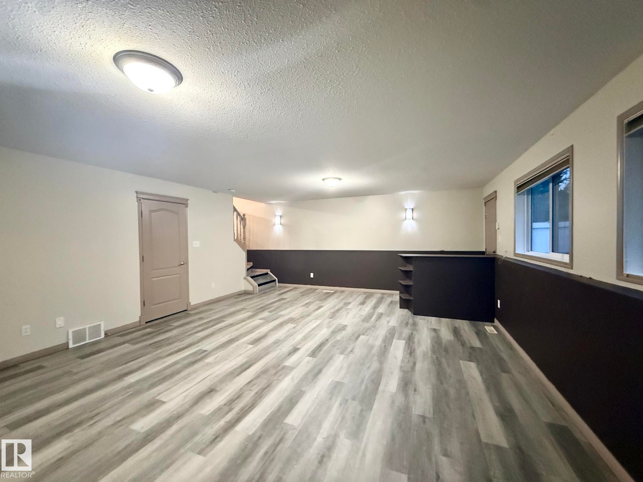Spacious room featuring wood-finish flooring, two-tone walls, recessed wall lighting, and built-in shelving - 1978 Tomlinson Green Green, Edmonton, AB