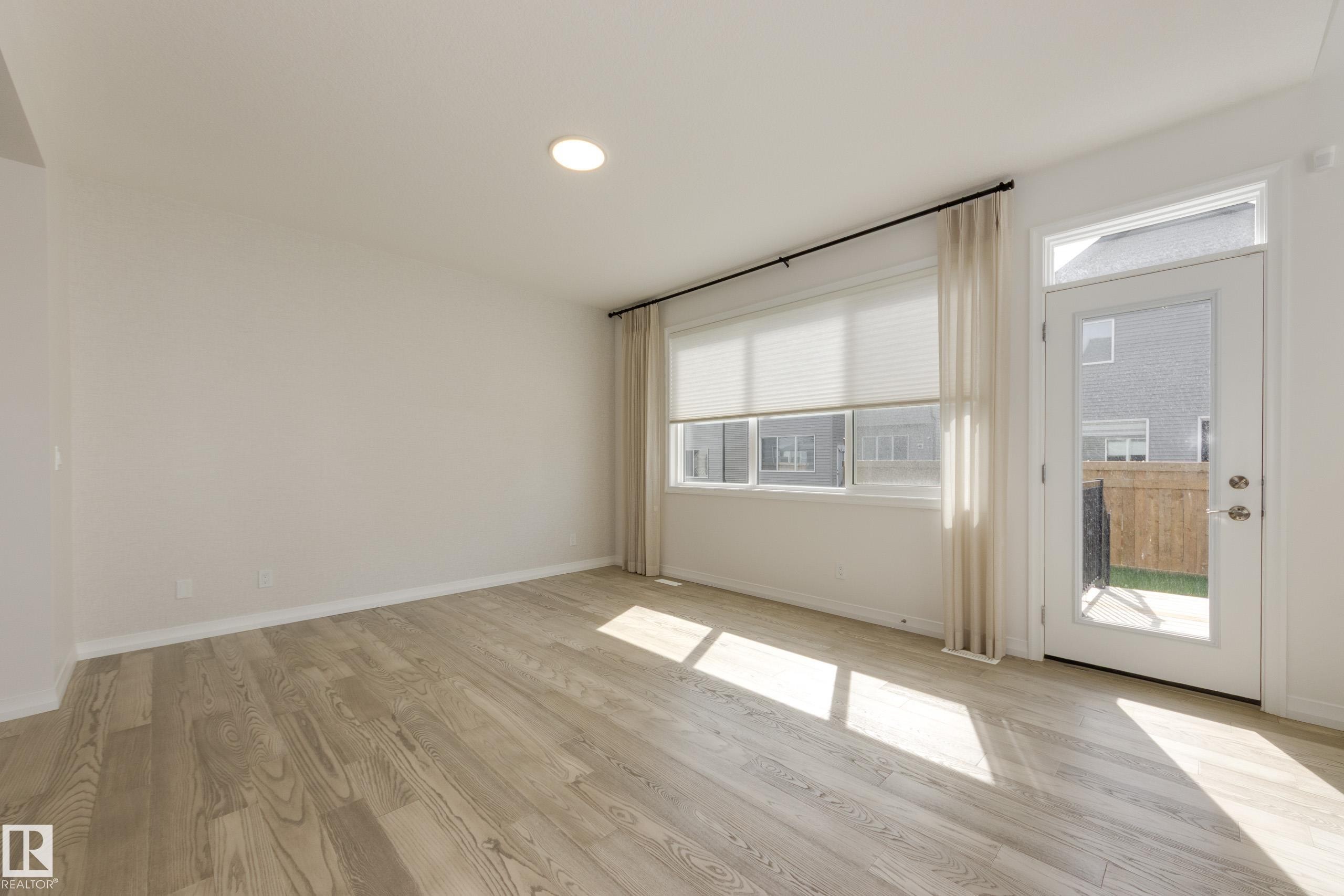 Open interior space featuring wood-finish flooring, recessed ceiling lighting, and a white color palette - 3249 Dixon Way Sw, Edmonton, AB