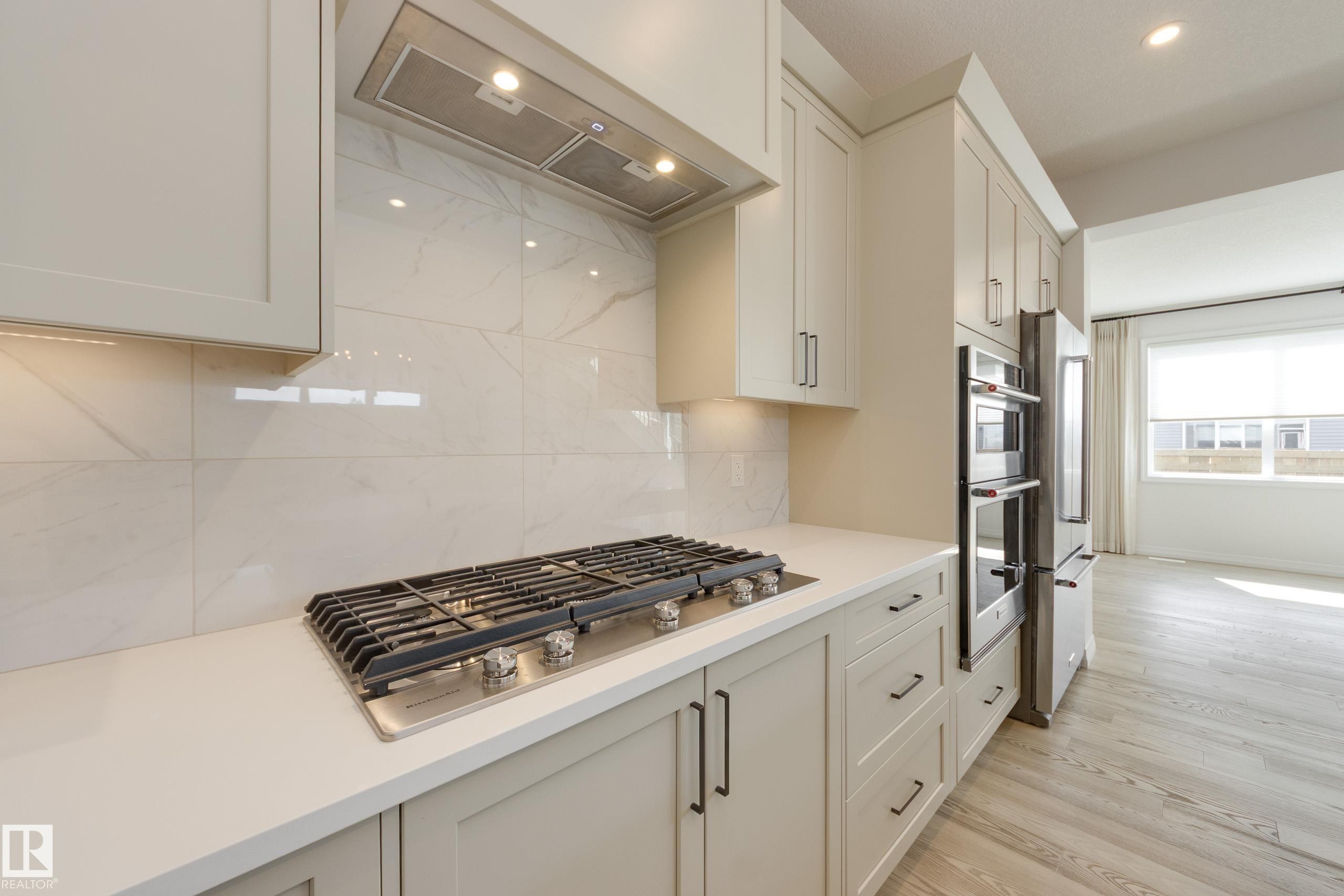 Kitchen featuring a gas cooktop, integrated stainless steel double ovens, and a side-by-side refrigerator - 3249 Dixon Way Sw, Edmonton, AB