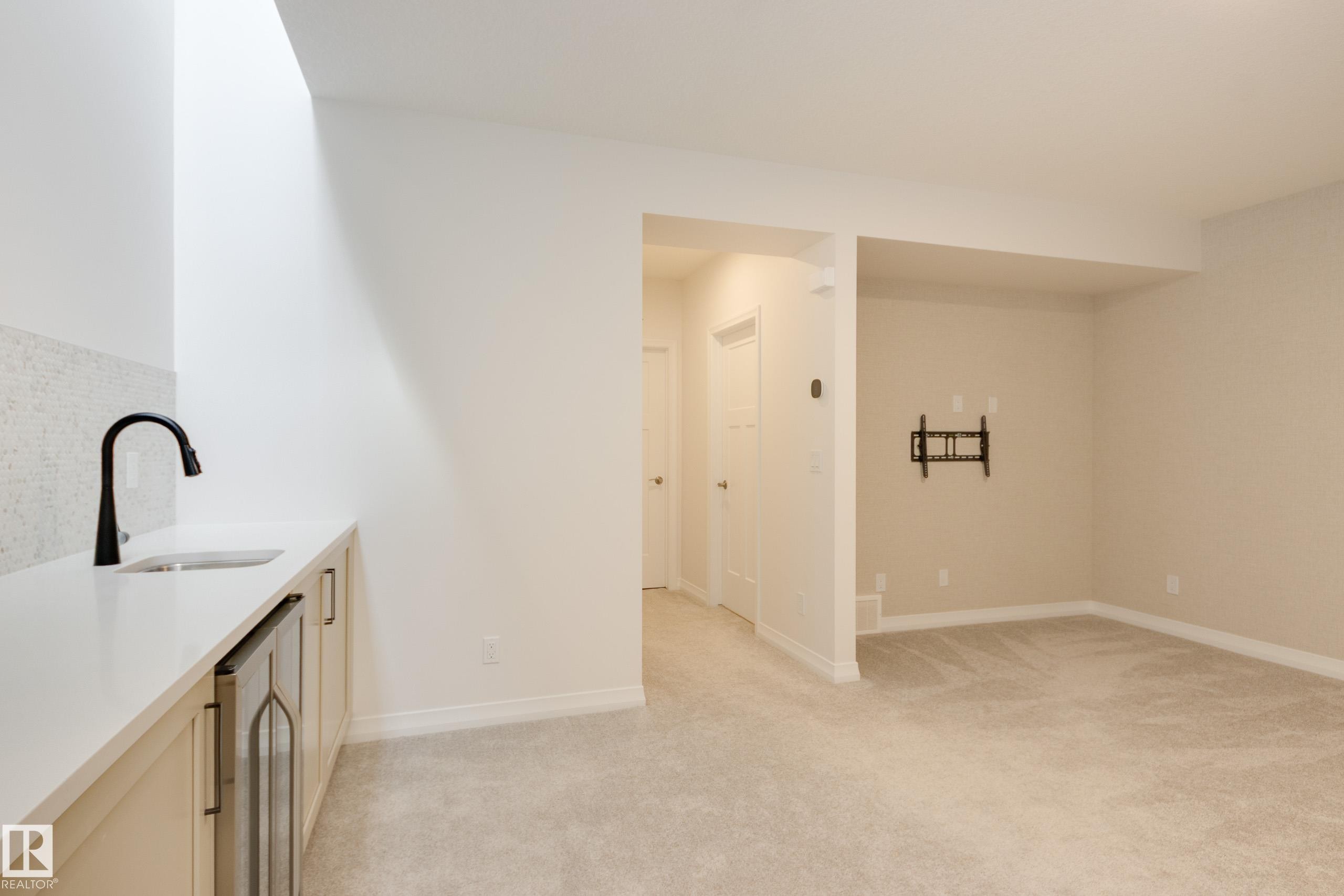 Wet bar featuring a solid surface countertop, undermount sink, and matte black faucet - 3249 Dixon Way Sw, Edmonton, AB