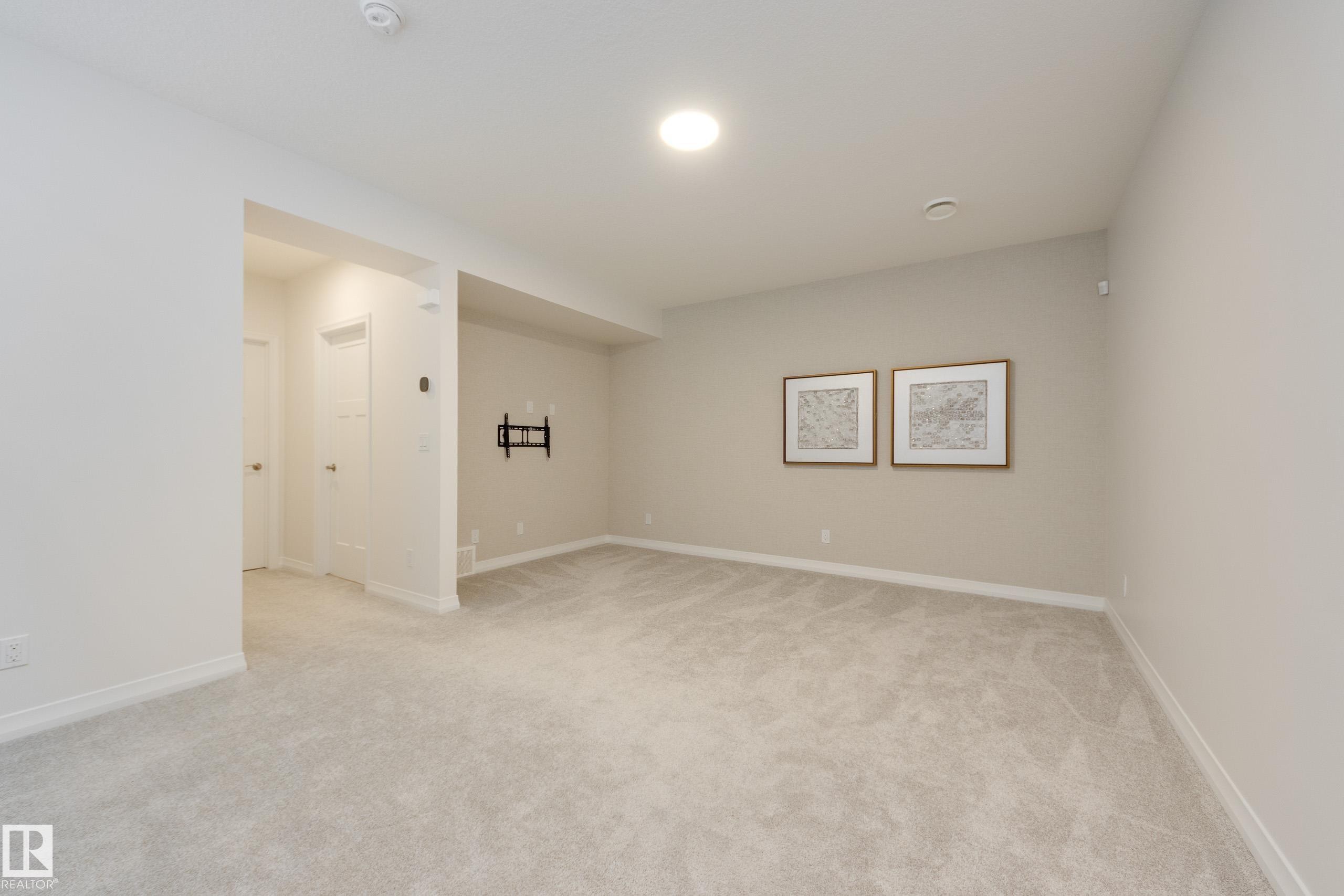 Spacious room featuring light-toned carpeting, neutral wall paint, and recessed ceiling lighting - 3249 Dixon Way Sw, Edmonton, AB