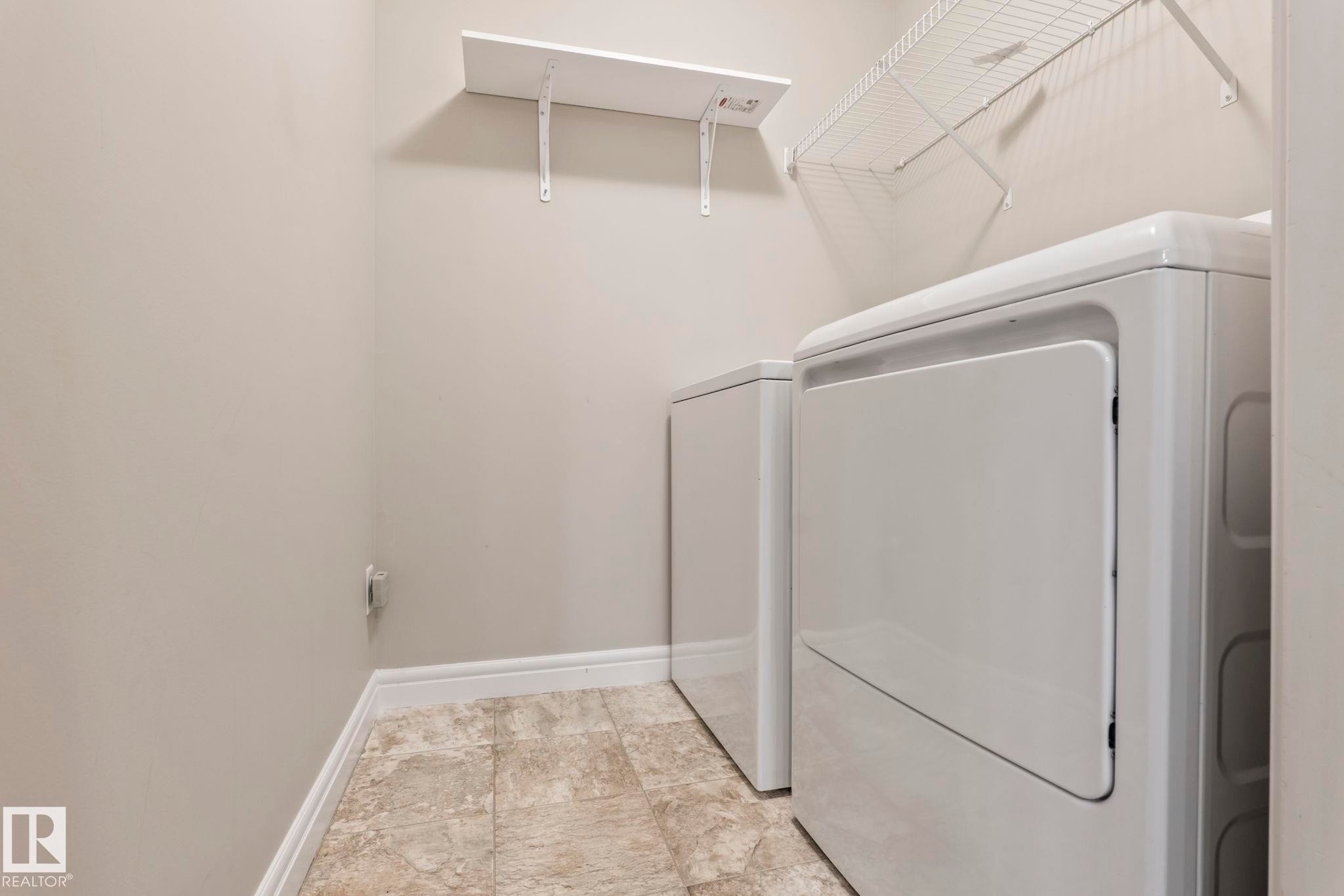 Dedicated laundry area featuring textured tile flooring and light-toned walls - 1542 33A St Nw, Edmonton, AB