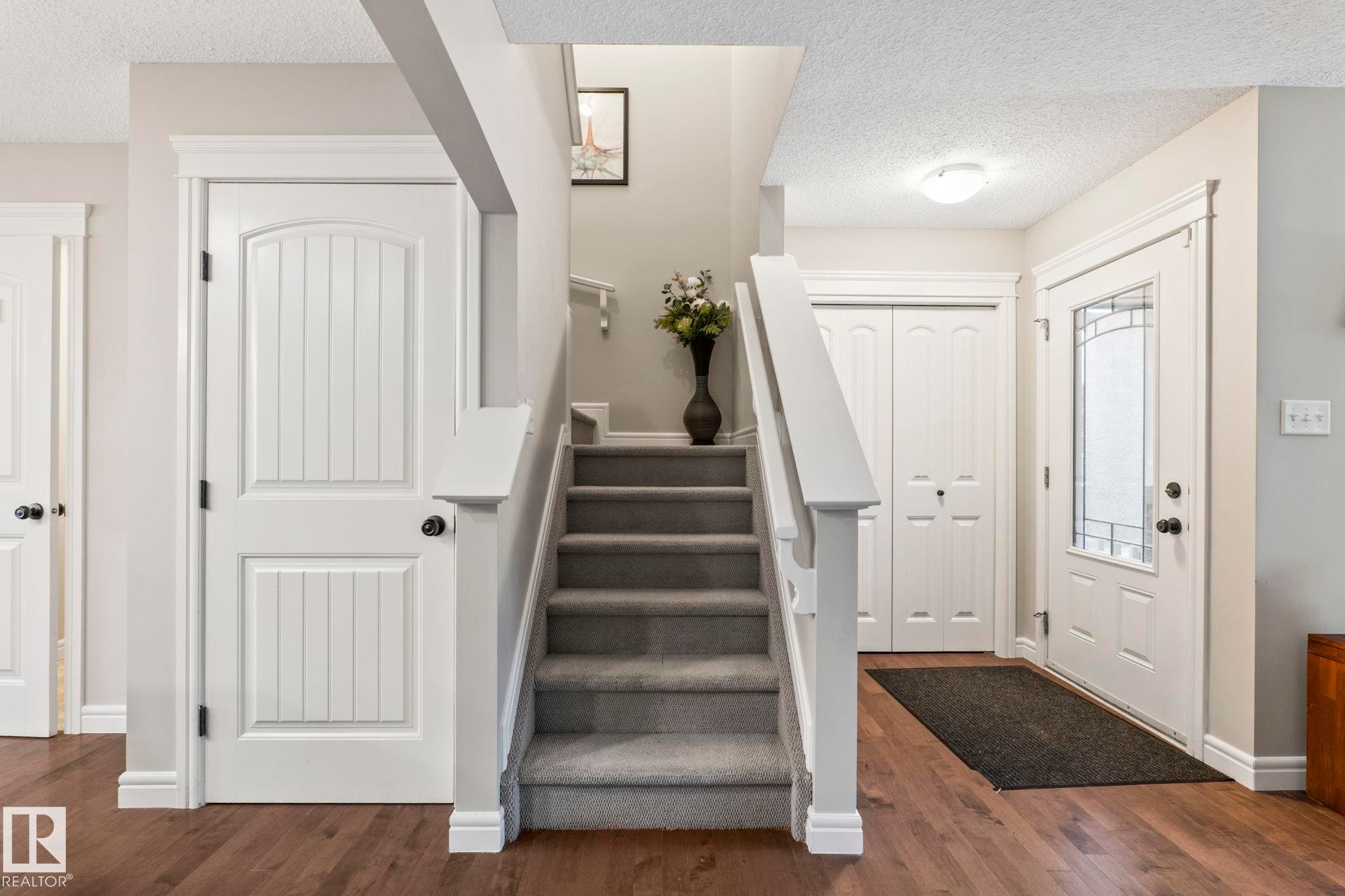 Staircase with carpeted treads and white wood-finish balusters - 1542 33A St Nw, Edmonton, AB