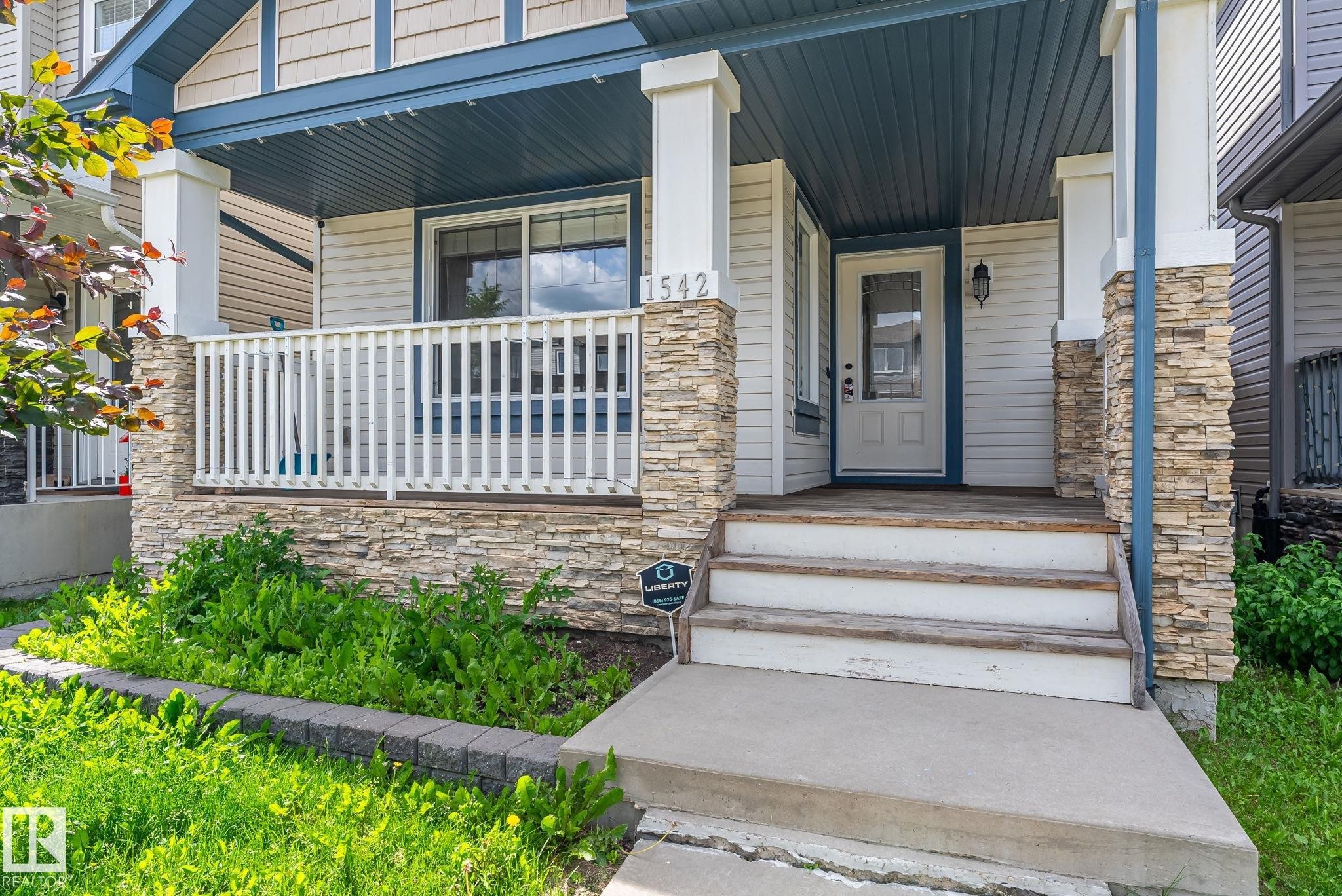 Front porch entry with stone accents, white railing, and blue ceiling detail - 1542 33A St Nw, Edmonton, AB