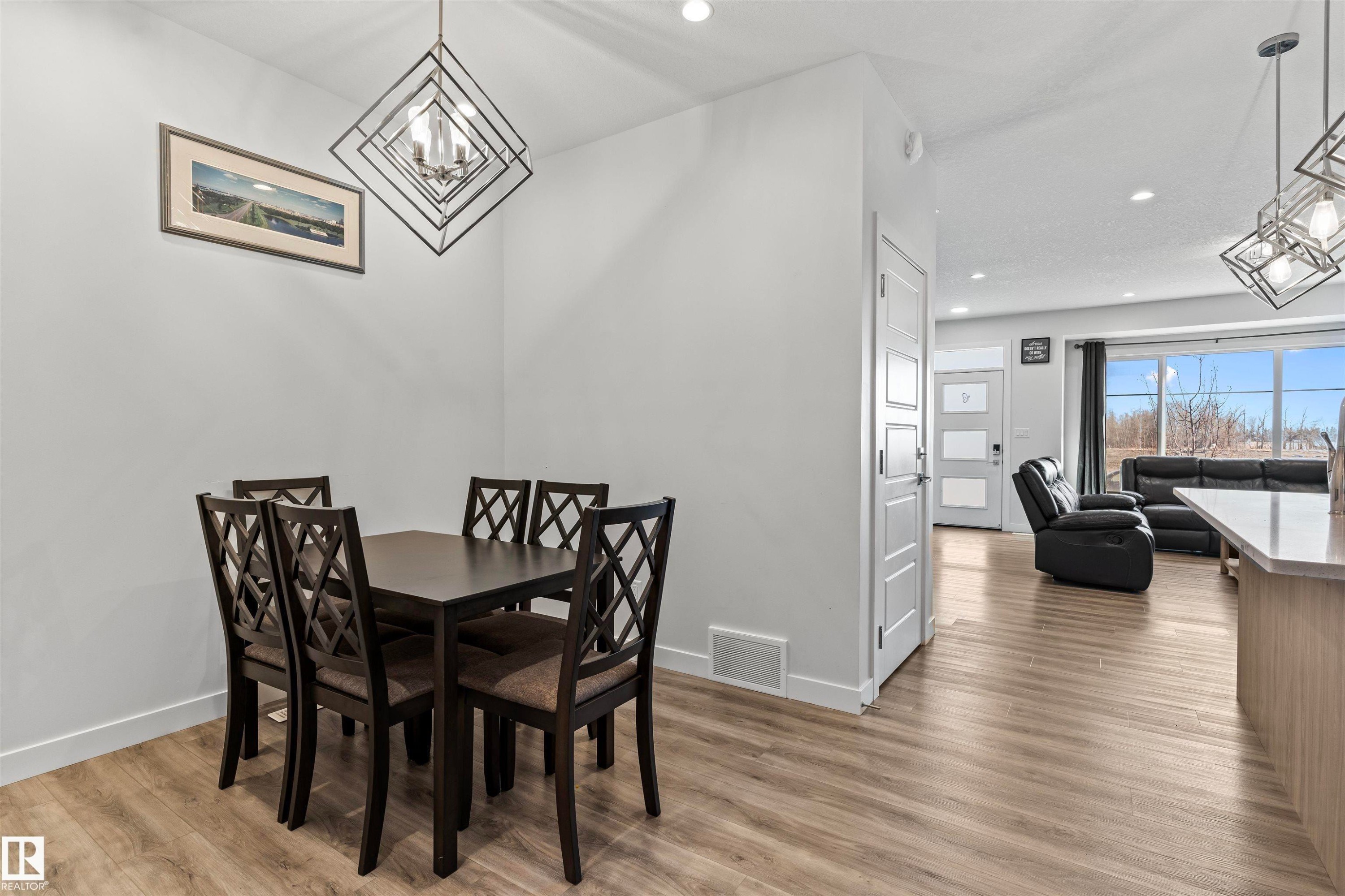 Dining area featuring a contemporary geometric chandelier and wood-finish flooring - 8046 Kiriak Link, Edmonton, AB - Indoor Photo Showing Dining Room