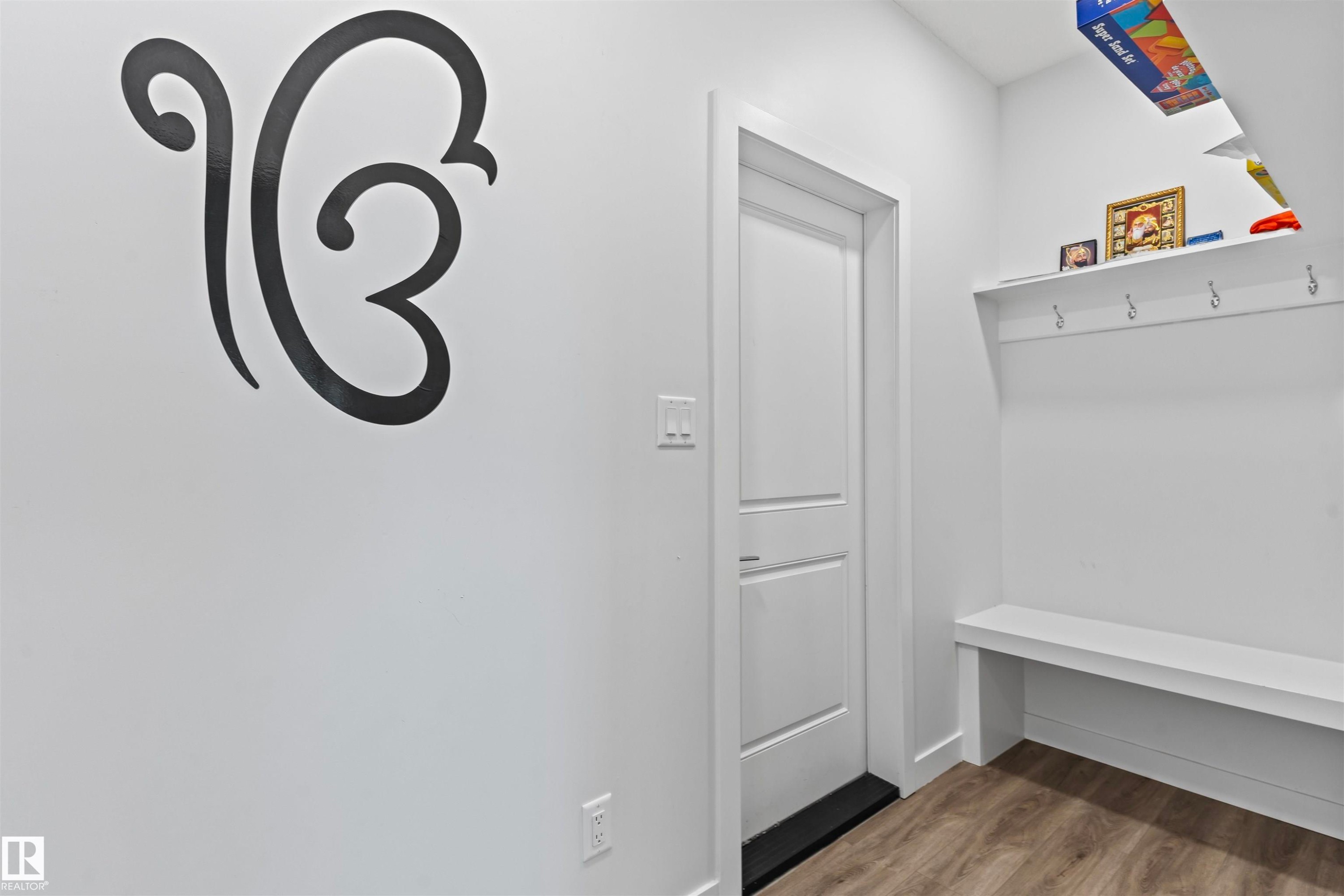Entryway featuring wood-finish flooring, a white paneled door, and built-in white shelving with integrated hooks and a bench - 8046 Kiriak Link, Edmonton, AB - Indoor Photo Showing Other Room