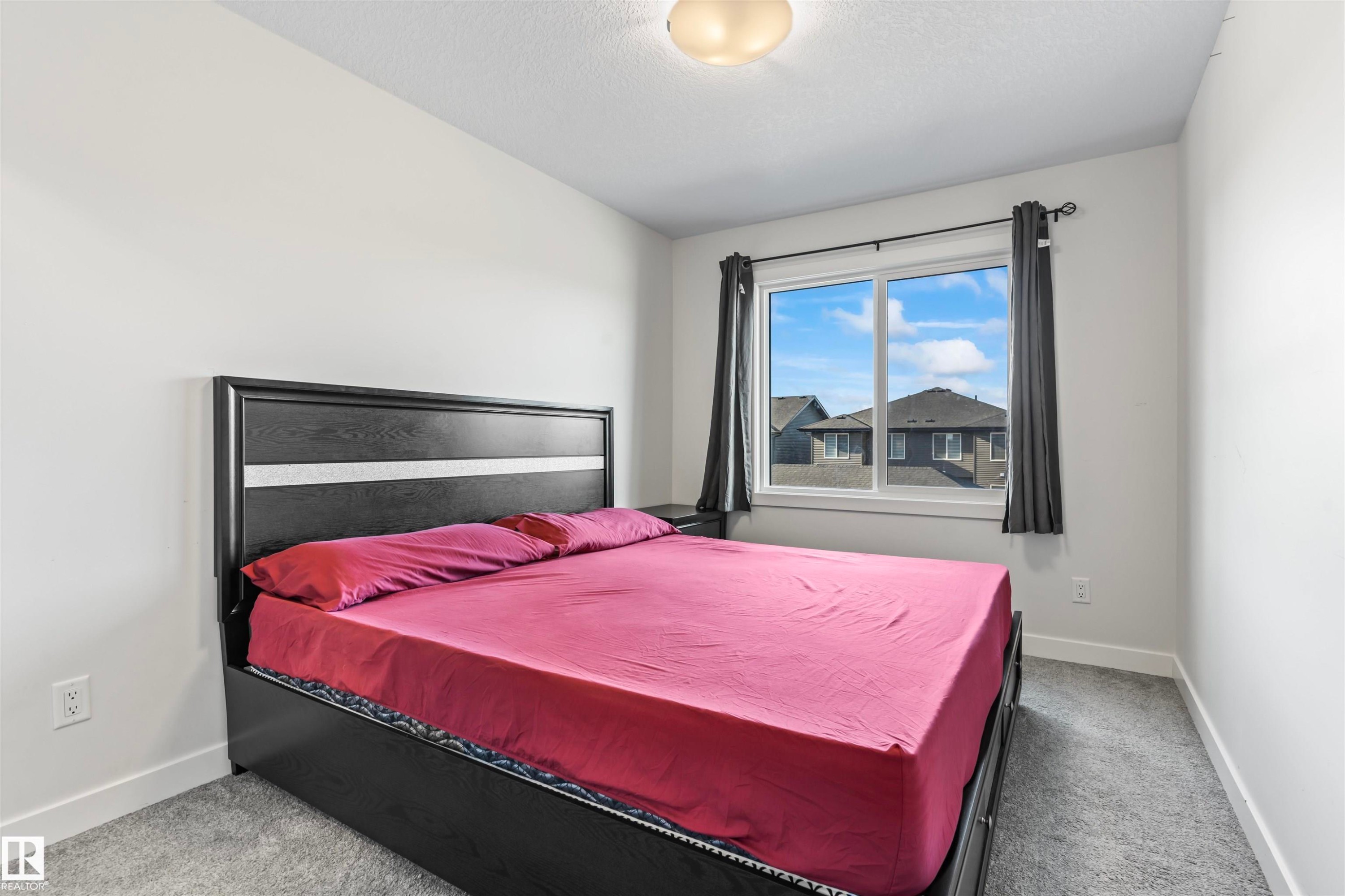 Bright room featuring a large window, soft grey carpeting, white baseboards, and a flush mount ceiling light fixture - 8046 Kiriak Link, Edmonton, AB - Indoor Photo Showing Bedroom