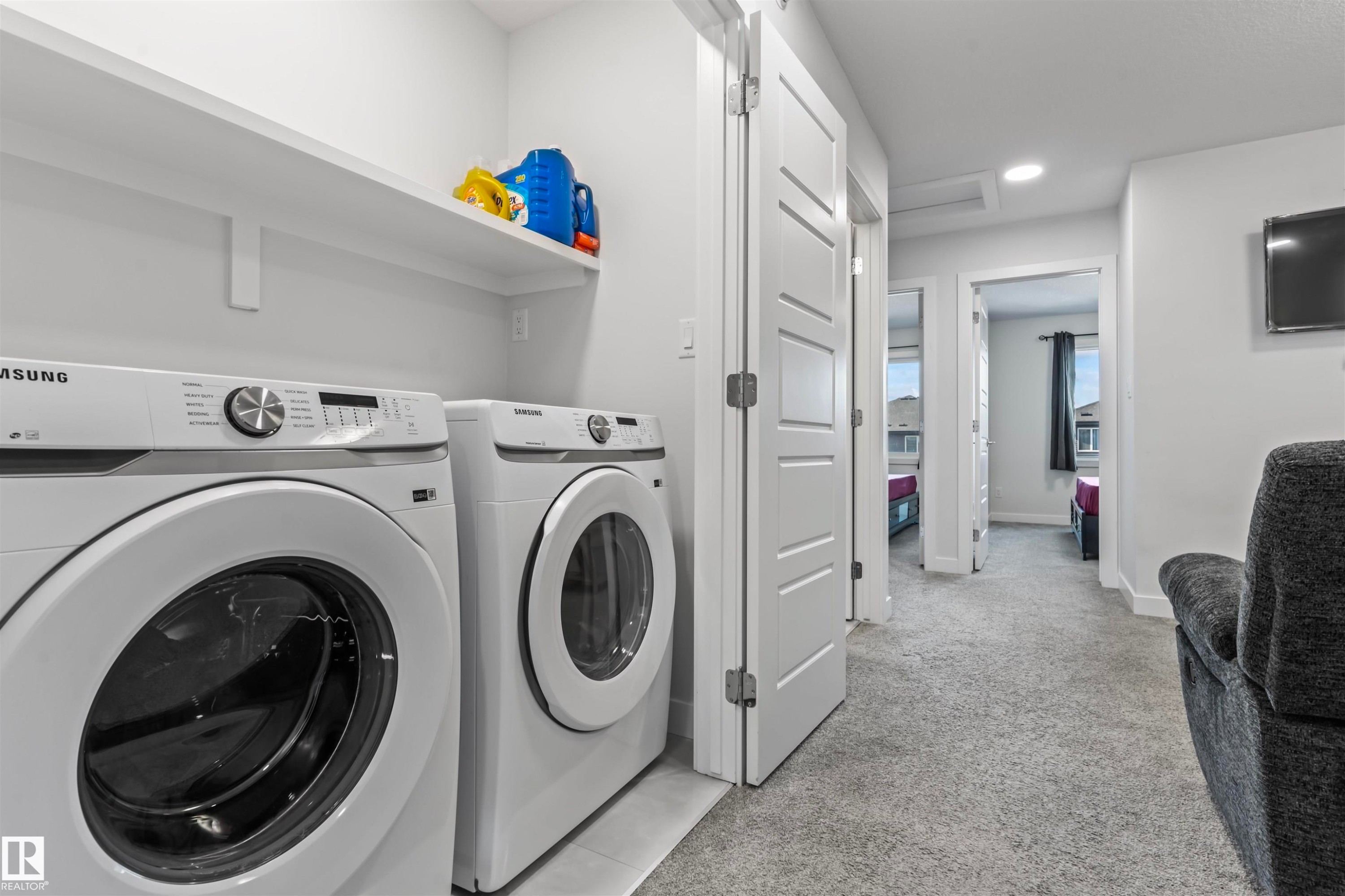 Dedicated laundry area with built-in shelving, two white front-loading appliances, and light grey wall paint - 8046 Kiriak Link, Edmonton, AB - Indoor Photo Showing Laundry Room