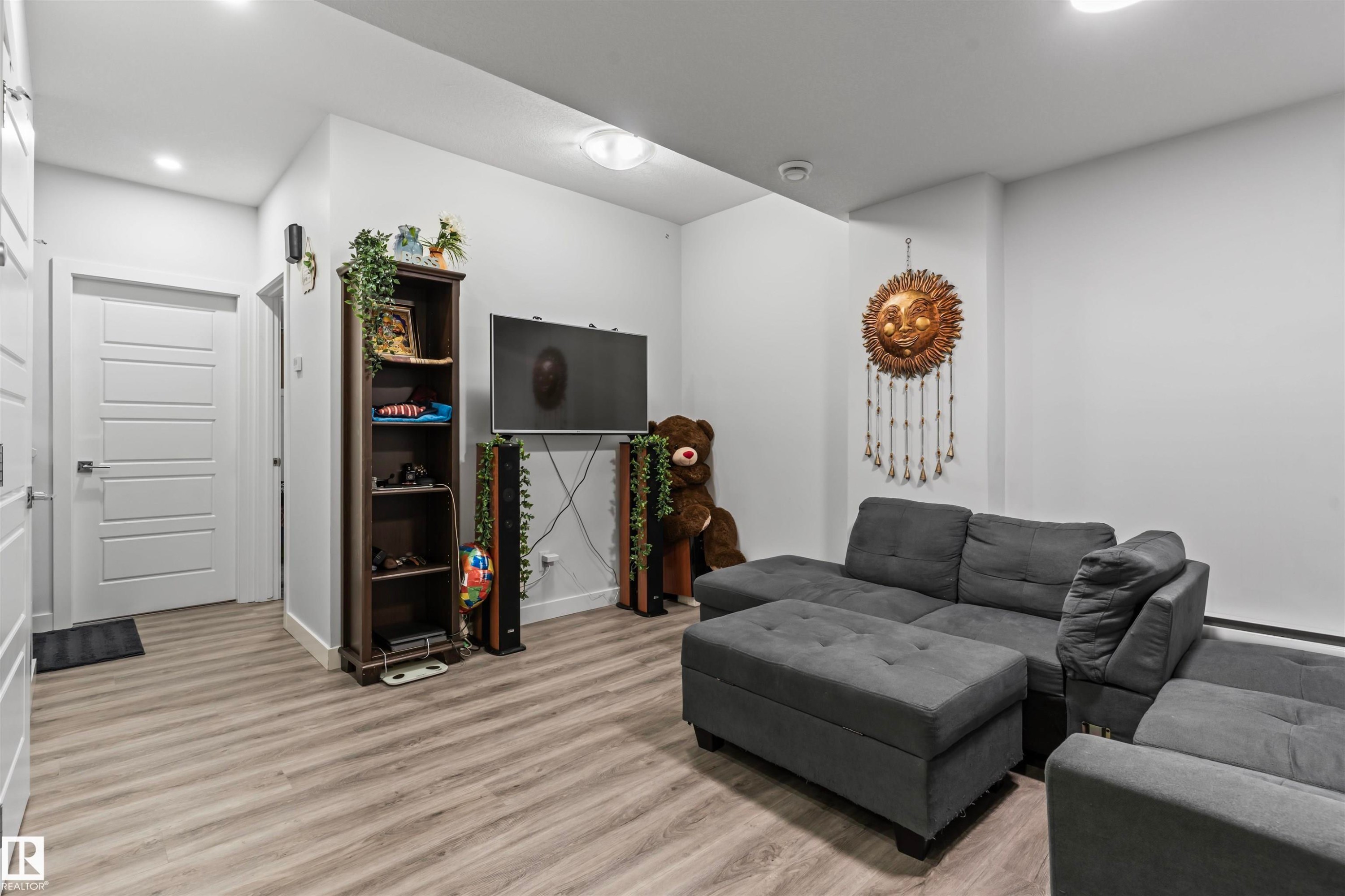 Contemporary living area featuring wood-finish flooring and recessed lighting - 8046 Kiriak Link, Edmonton, AB - Indoor