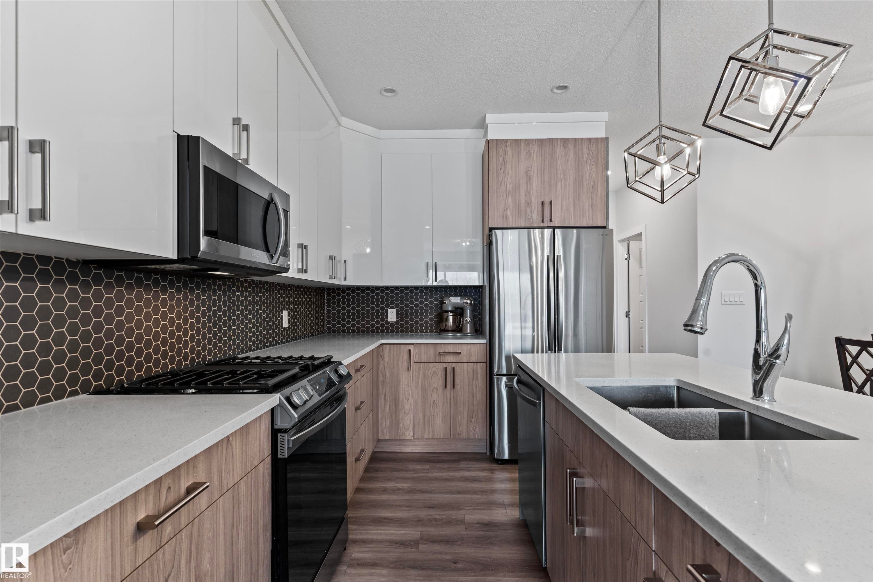 Modern kitchen featuring white upper cabinetry, wood-finish lower cabinetry, and light-toned countertops - 8046 Kiriak Link, Edmonton, AB - Indoor Photo Showing Kitchen With Double Sink With Upgraded Kitchen