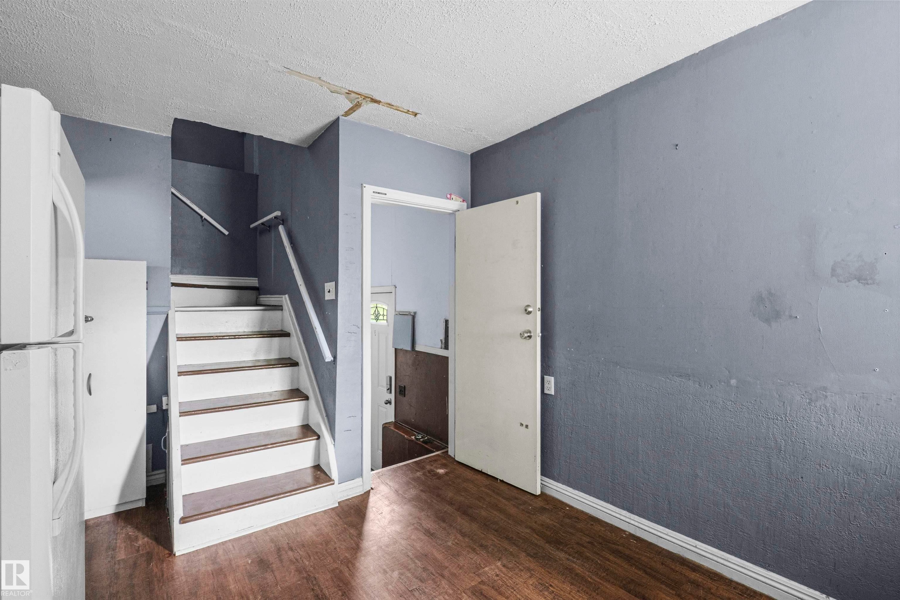 Wood-finish flooring throughout, complemented by a white-painted staircase with wood-finish treads - 7520 106 Street, Edmonton, AB