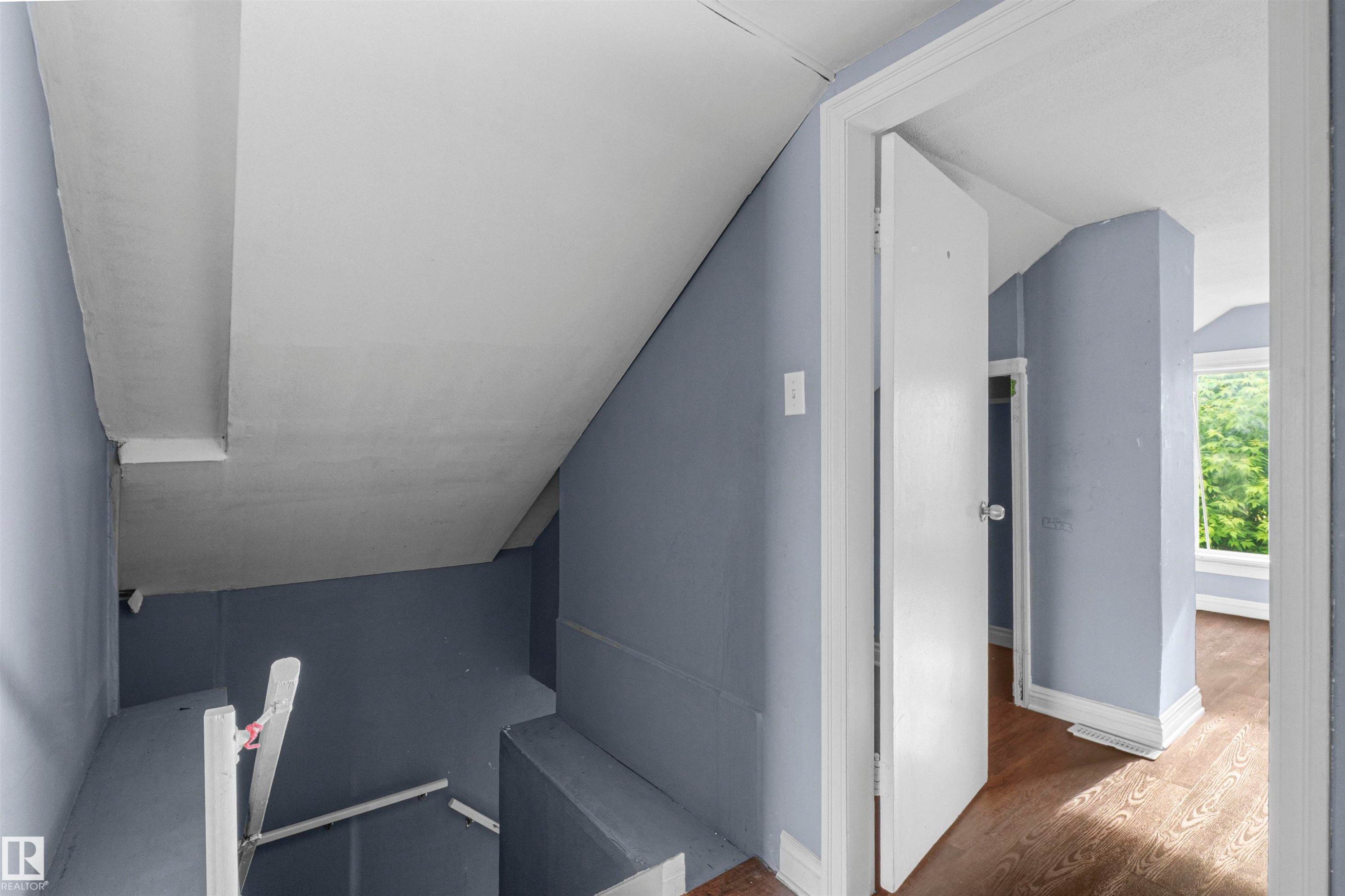Sloped ceiling interior with light blue walls and wood-finish flooring - 7520 106 Street, Edmonton, AB