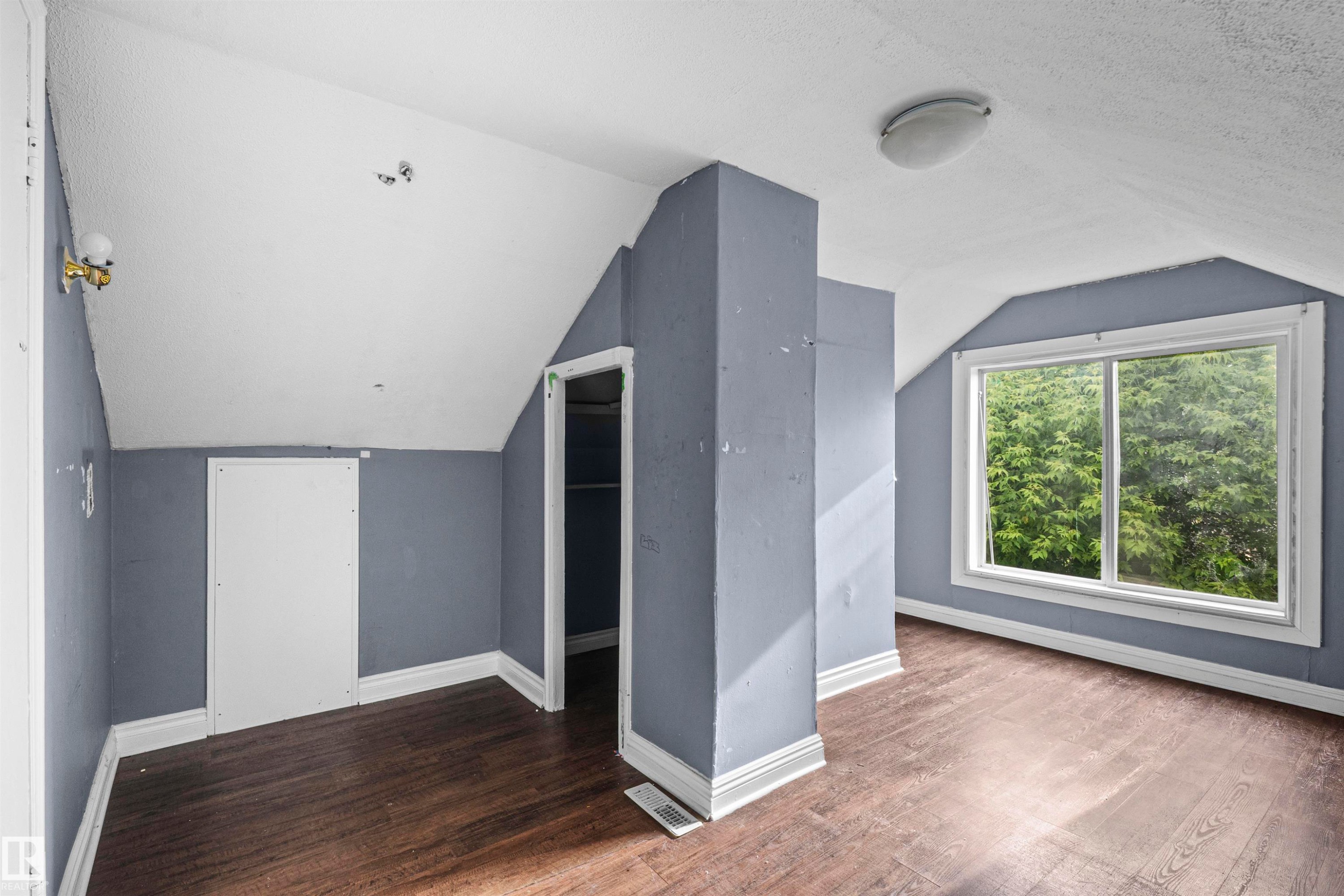 Attic space with sloped ceilings, wood-finish flooring, a contemporary window, and a built-in storage area - 7520 106 Street, Edmonton, AB