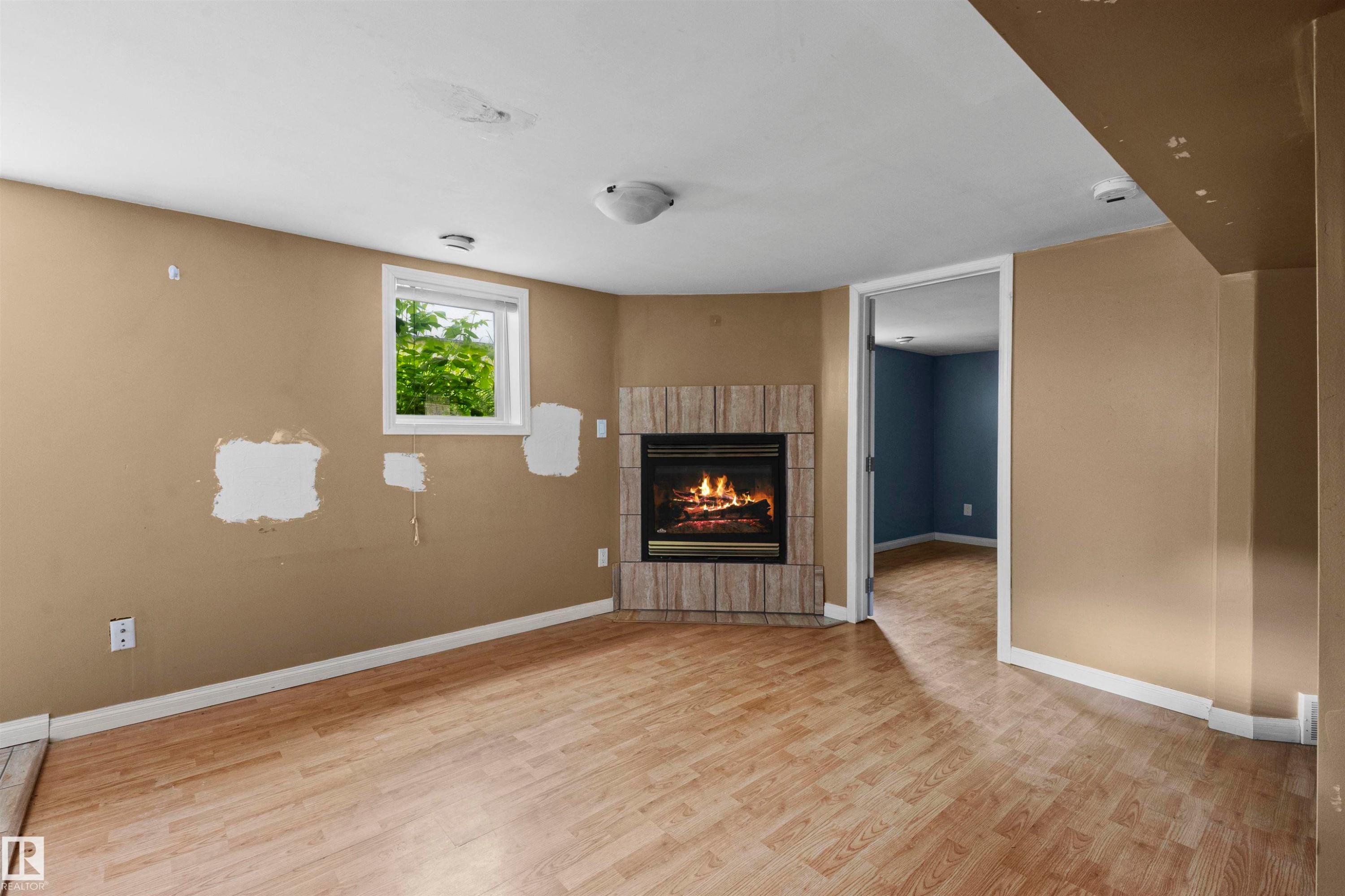 Recreational space featuring wood-finish flooring, a corner fireplace with a stacked stone surround, and an egress window - 7520 106 Street, Edmonton, AB