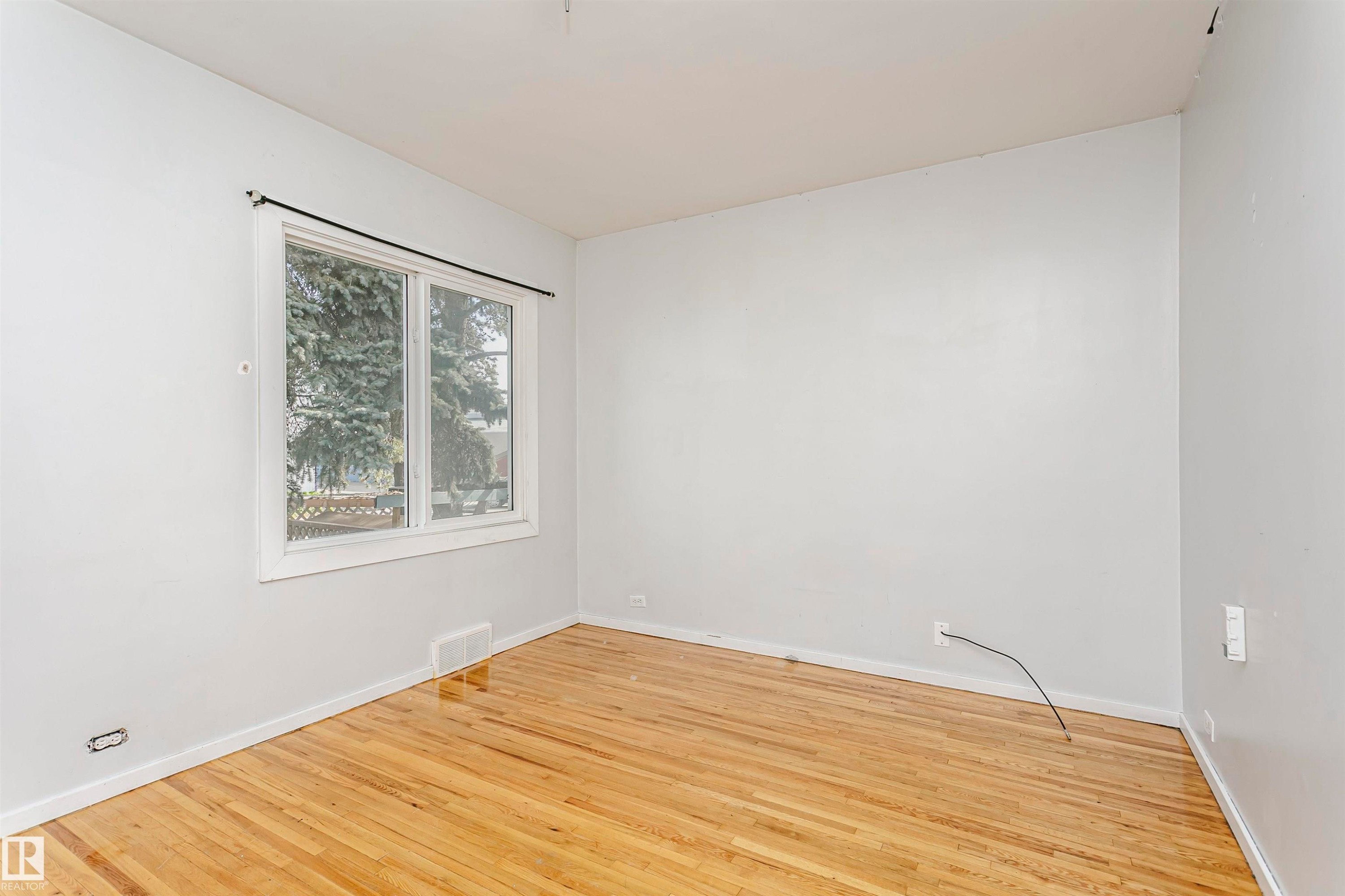 Light wood-finish flooring provides a warm base for this room featuring light gray walls - 10035 81 Avenue Nw, Edmonton, AB - Indoor Photo Showing Other Room