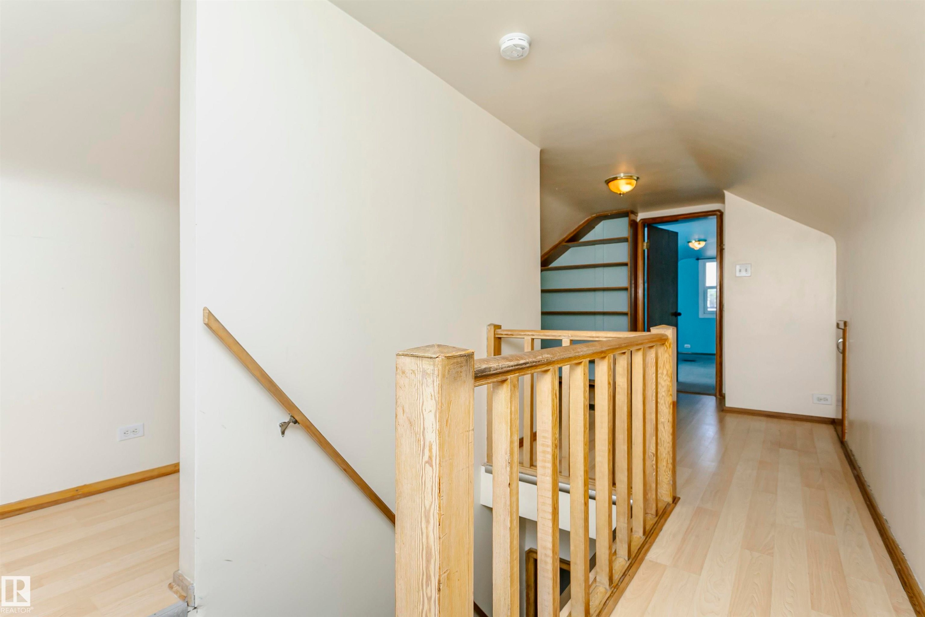 Upper-level hallway with wood-finish flooring, light-toned walls, and a natural wood staircase railing - 10035 81 Avenue Nw, Edmonton, AB - Indoor Photo Showing Other Room