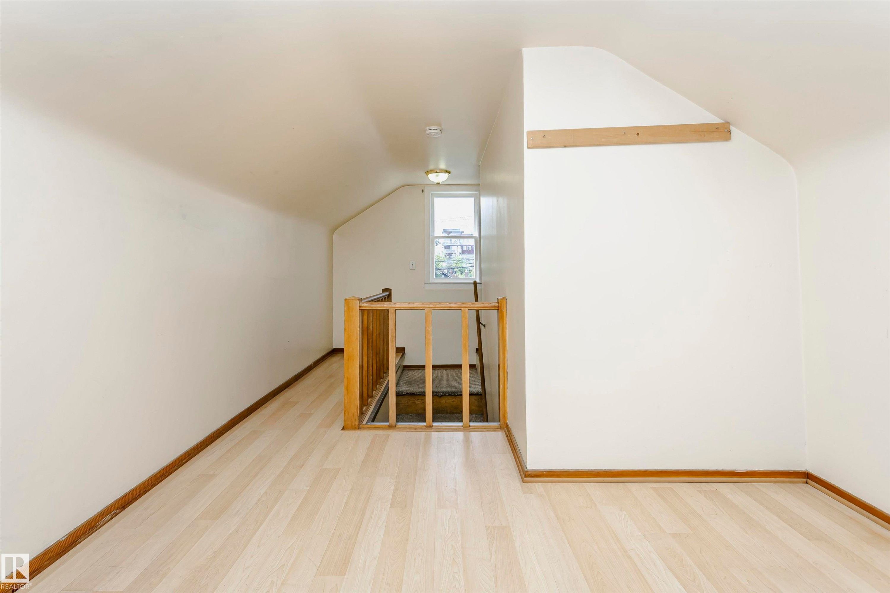Attic space featuring wood-finish flooring, white walls, and a window providing natural light - 10035 81 Avenue Nw, Edmonton, AB - Indoor Photo Showing Other Room