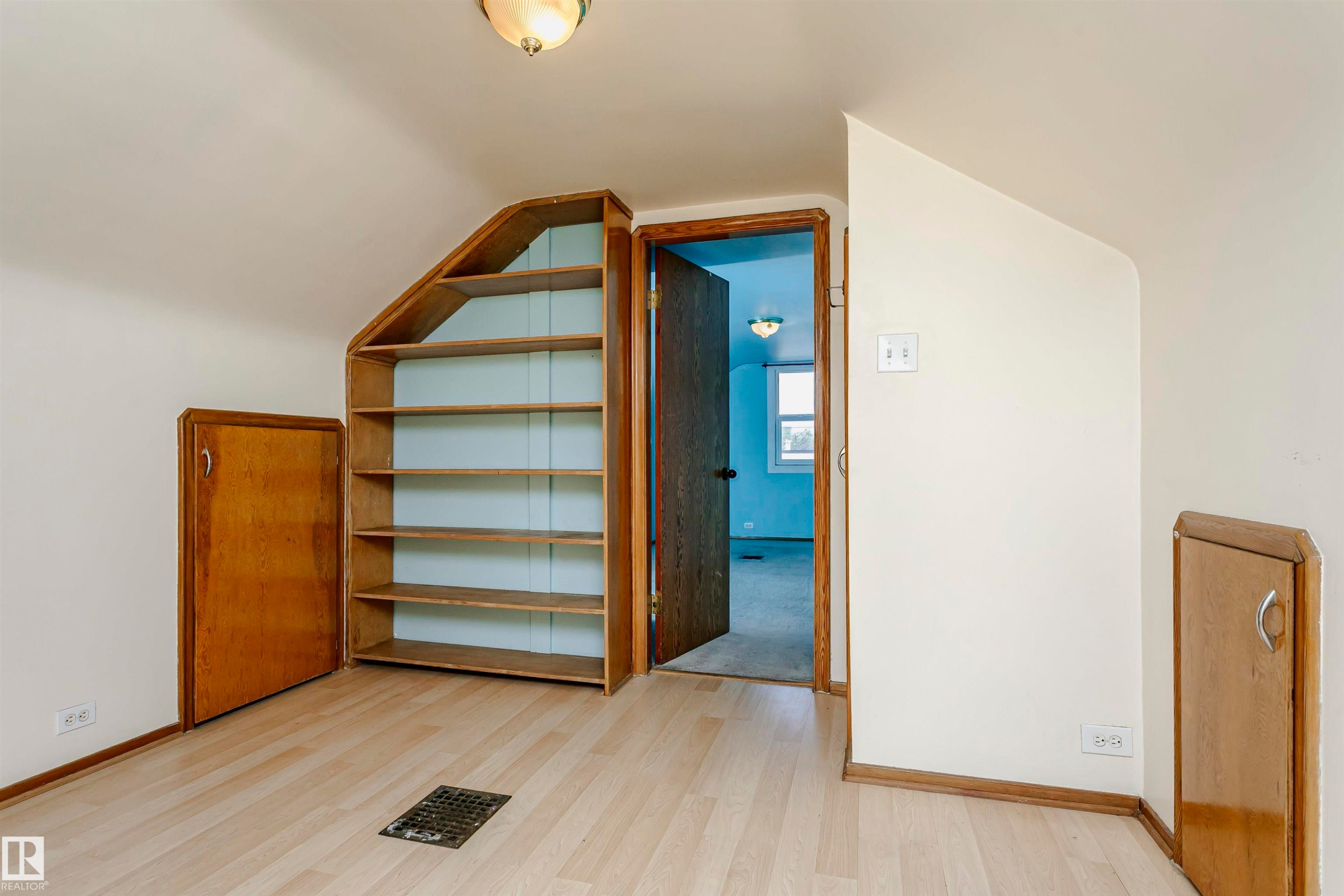 Light wood-finish flooring with an angled ceiling - 10035 81 Avenue Nw, Edmonton, AB - Indoor Photo Showing Other Room