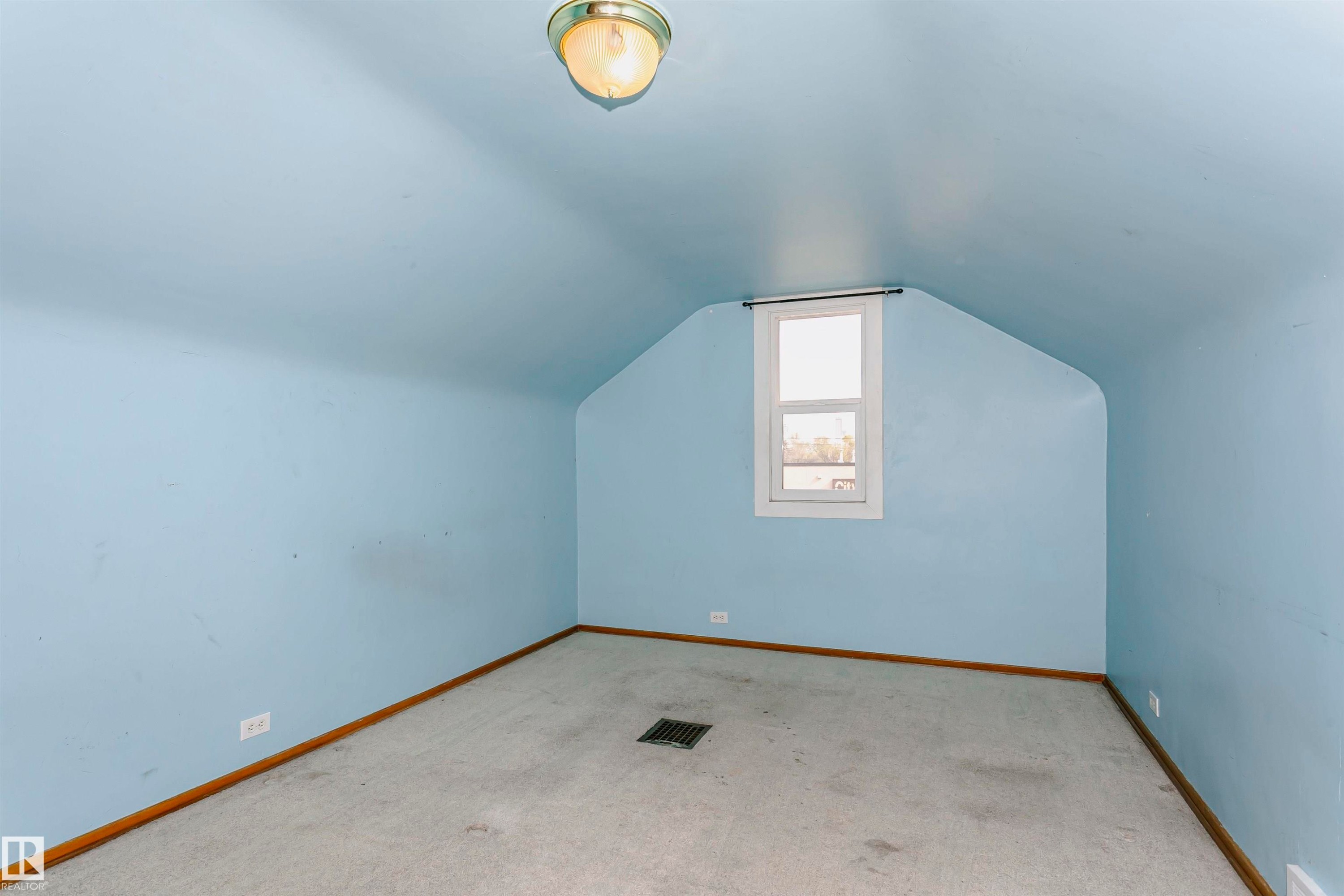 Attic space featuring sloped ceilings, a centered window, wall-to-wall carpeting, and wood baseboards - 10035 81 Avenue Nw, Edmonton, AB - Indoor Photo Showing Other Room