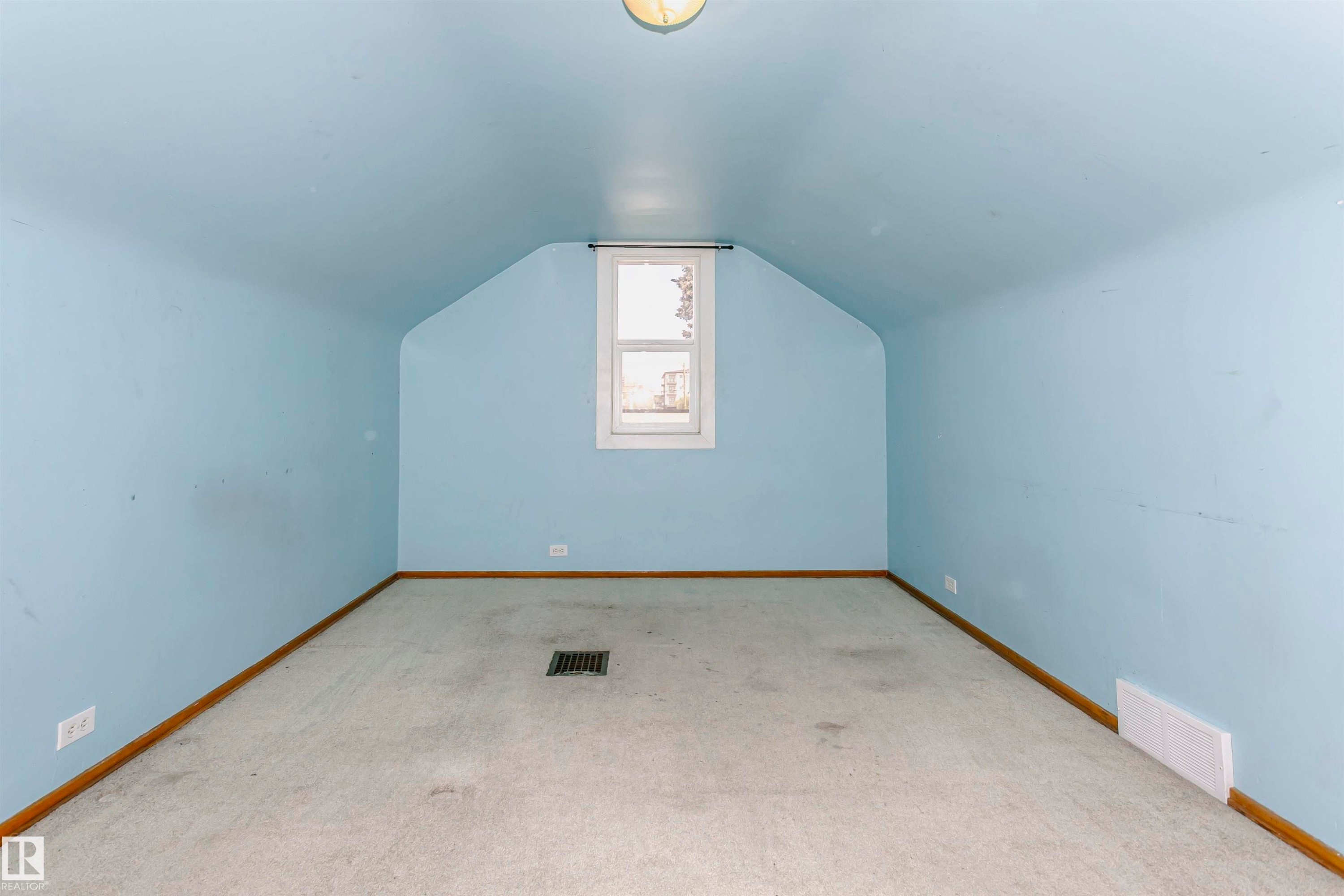 Room featuring sloped ceilings, light blue painted walls, neutral carpet, a single window, and a flush-mount ceiling light fixture - 10035 81 Avenue Nw, Edmonton, AB - Indoor Photo Showing Other Room