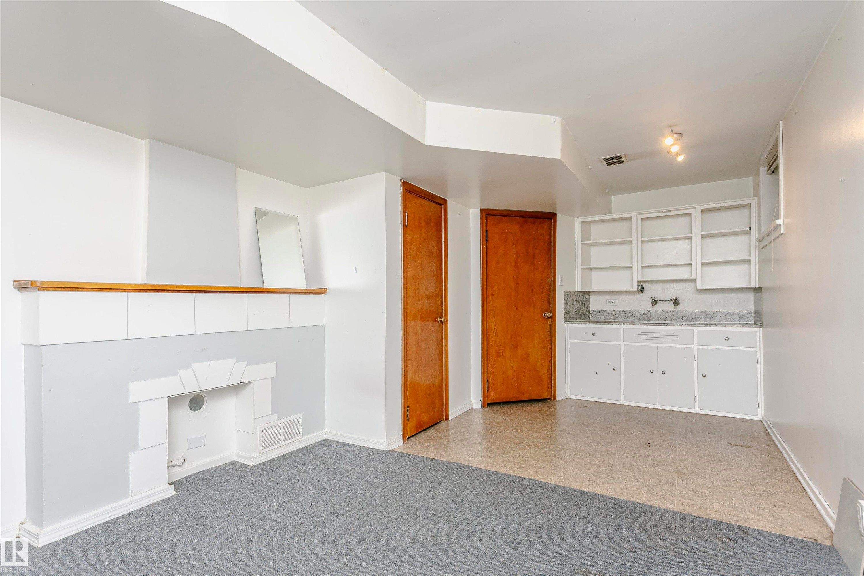 Room featuring a built-in decorative fireplace, grey carpeting, and light-toned walls - 10035 81 Avenue Nw, Edmonton, AB - Indoor Photo Showing Other Room
