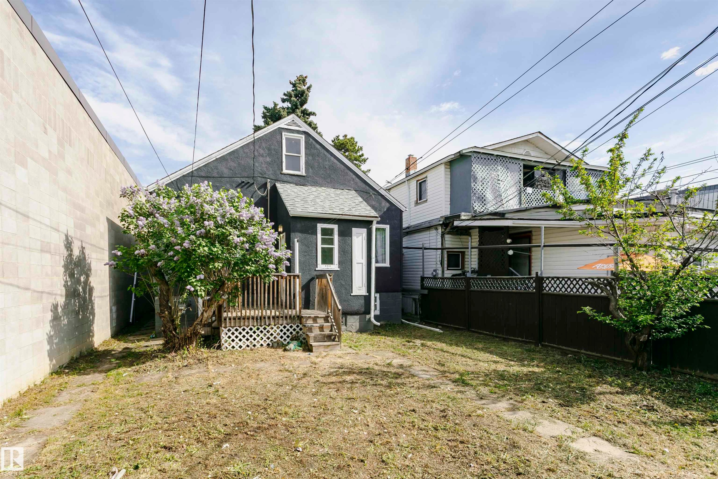 Rear exterior of a dark-toned residential structure featuring white trim windows and a gabled roof - 10035 81 Avenue Nw, Edmonton, AB - Outdoor