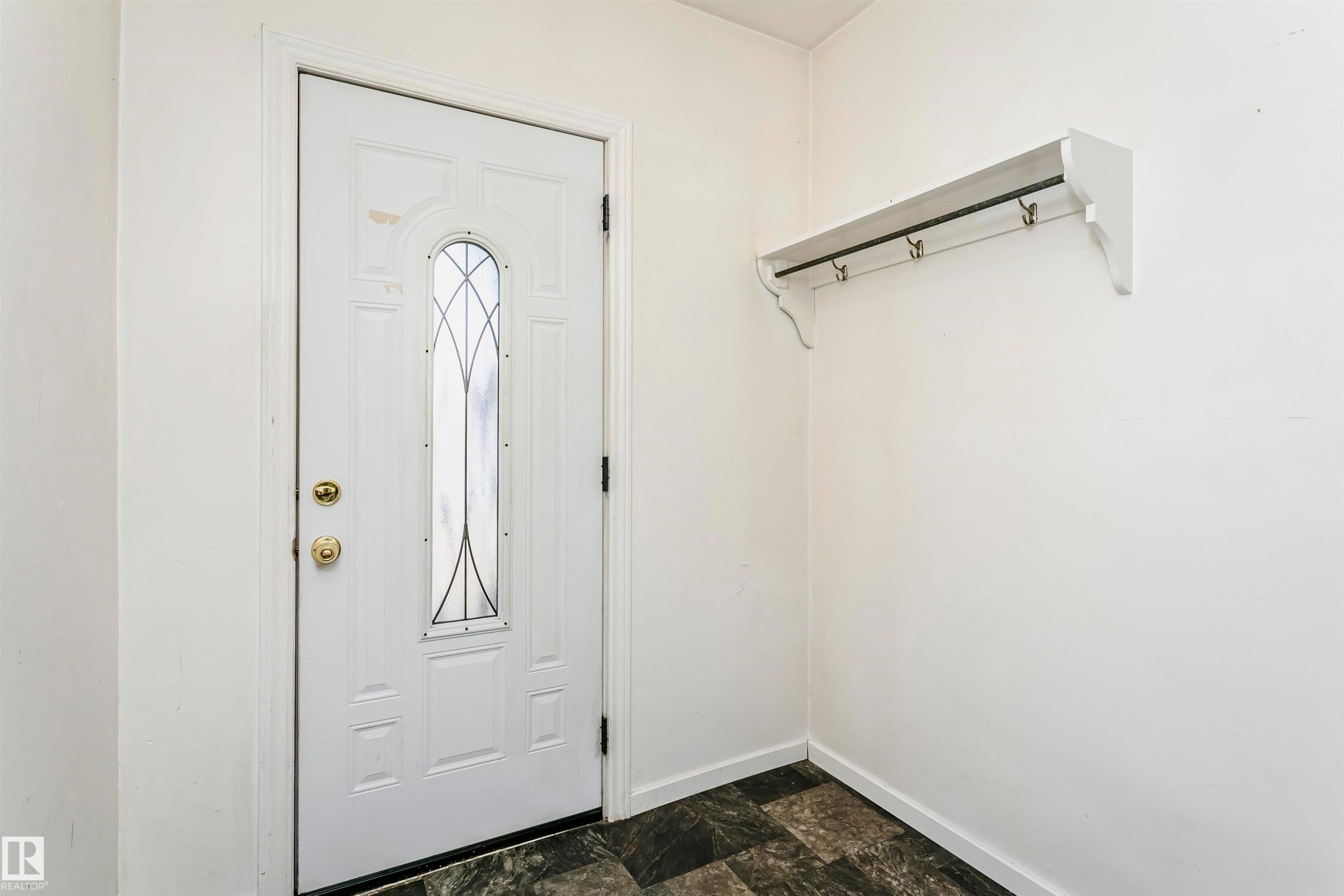 Entryway featuring a white door with decorative glass insert, brass hardware, and contrasting dark flooring - 10035 81 Avenue Nw, Edmonton, AB - Indoor